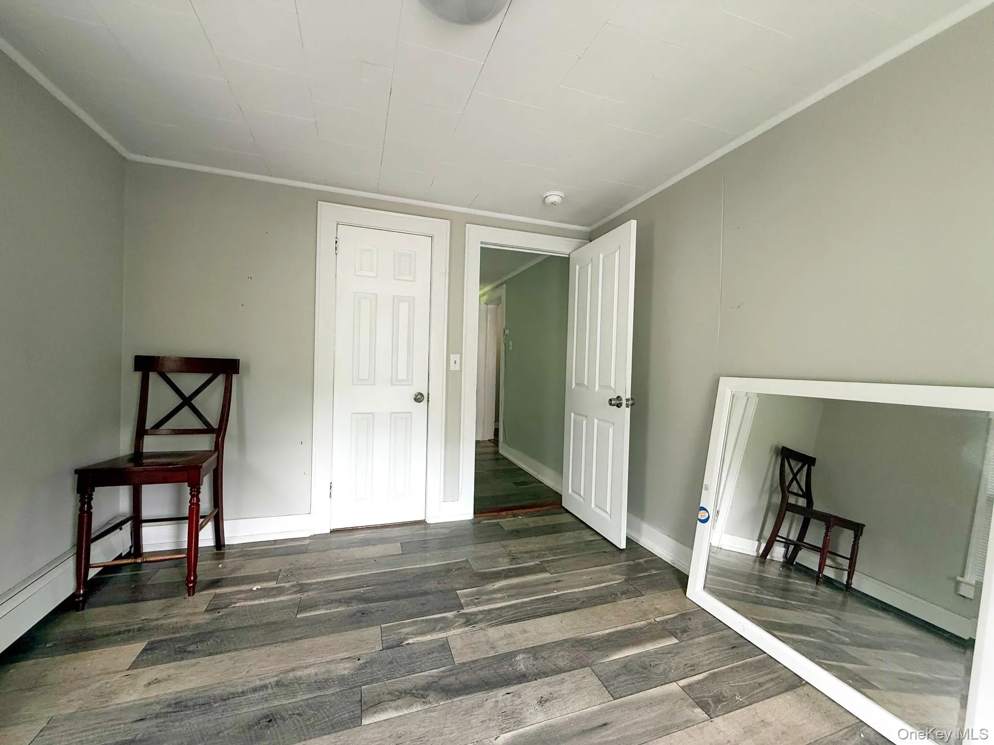 Unfurnished bedroom featuring wood finished floors and ornamental molding Unfurnished bedroom featuring wood finished floors and ornamental molding
