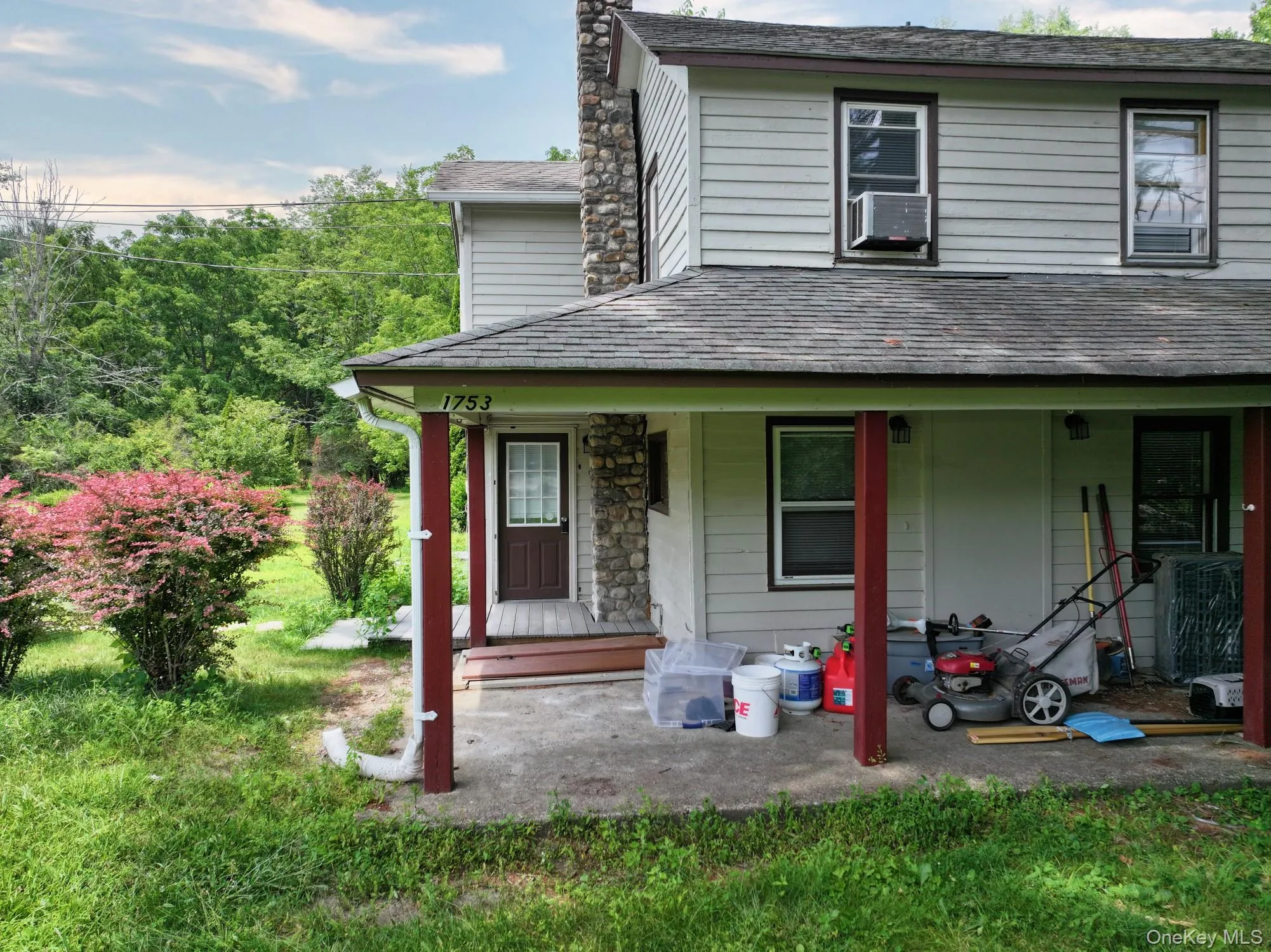 View of front of house featuring covered porch, a chimney, cooling unit, and stone siding View of front of house featuring covered porch, a chimney, cooling unit, and stone siding