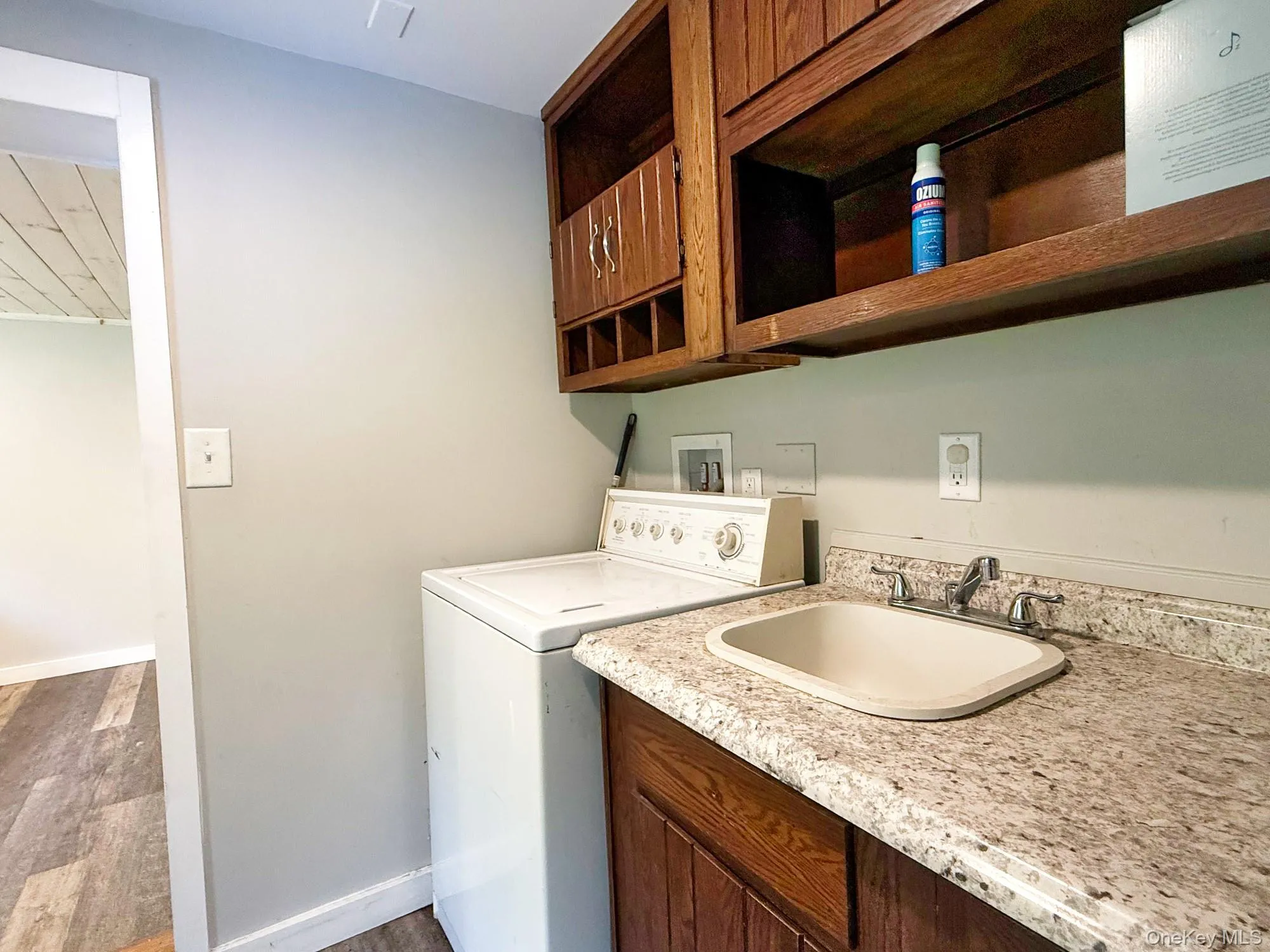 Washroom with washer / clothes dryer, cabinet space, and wood finished floors Washroom with washer / clothes dryer, cabinet space, and wood finished floors