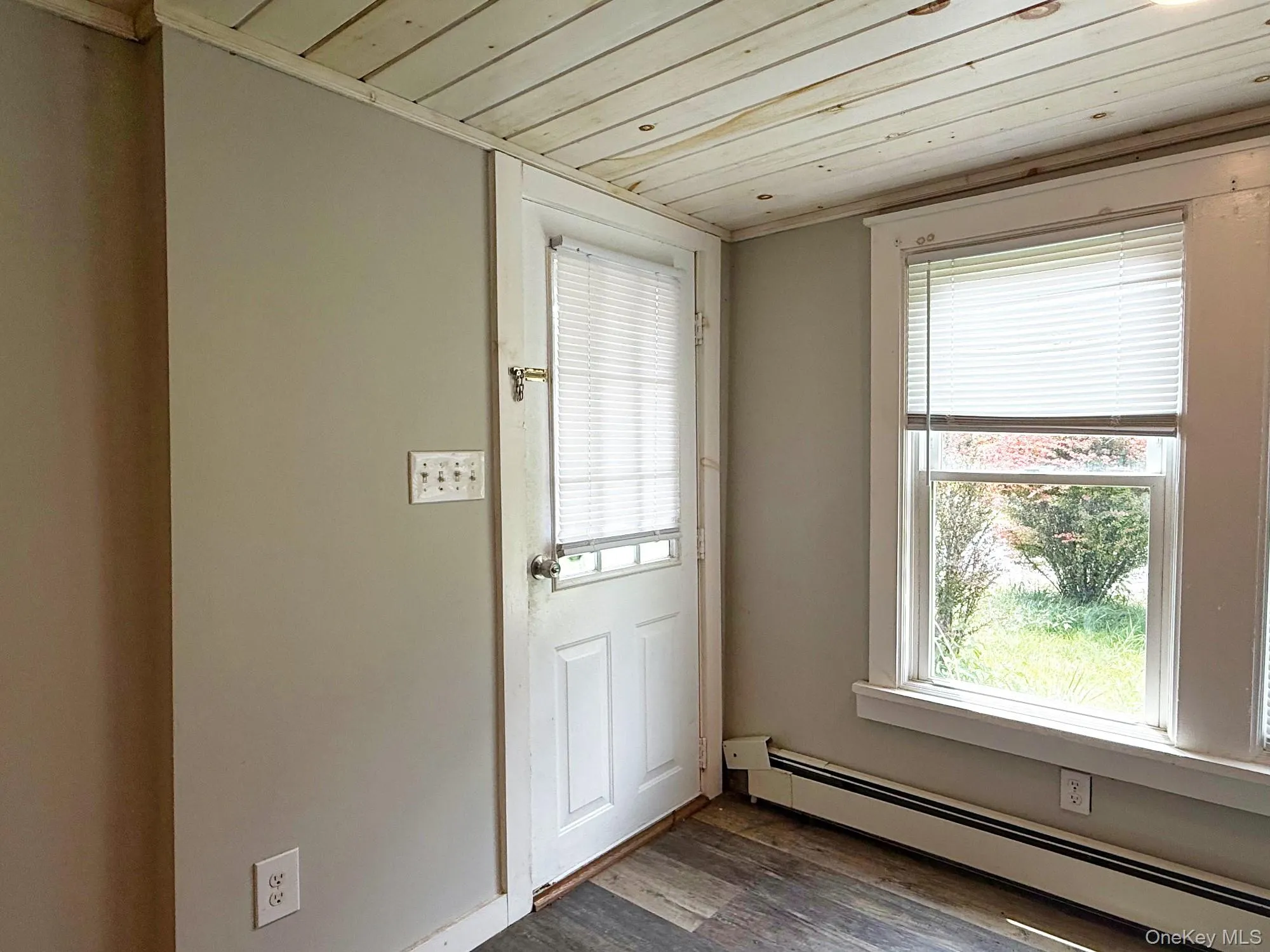 Doorway with a baseboard heating unit, wooden ceiling, and dark wood-type flooring Doorway with a baseboard heating unit, wooden ceiling, and dark wood-type flooring