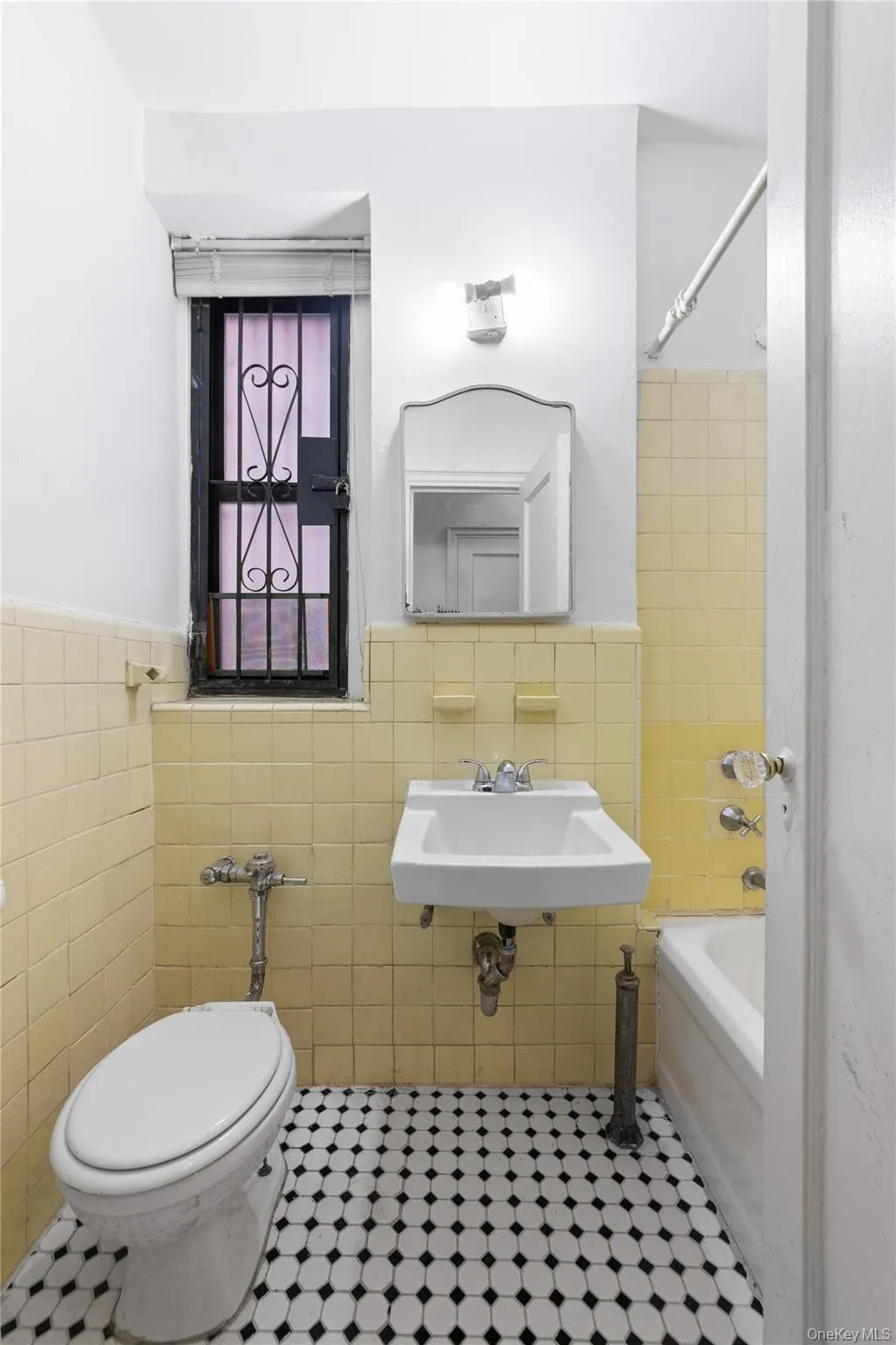 Full bathroom with tile walls, tile patterned floors, a wainscoted wall, bathtub / shower combination, and toilet Full bathroom with tile walls, tile patterned floors, a wainscoted wall, bathtub / shower combination, and toilet