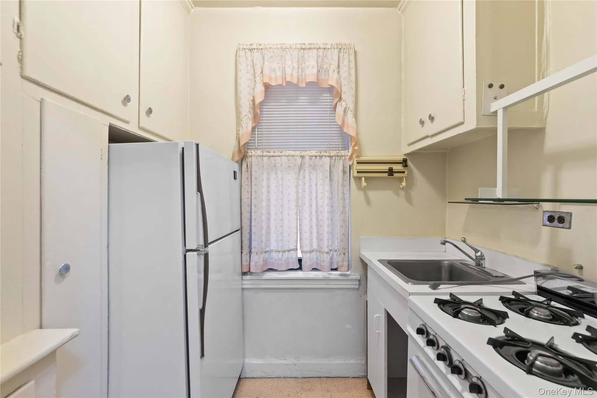 Kitchen with range with gas cooktop, freestanding refrigerator, a sink, and light countertops Kitchen with range with gas cooktop, freestanding refrigerator, a sink, and light countertops