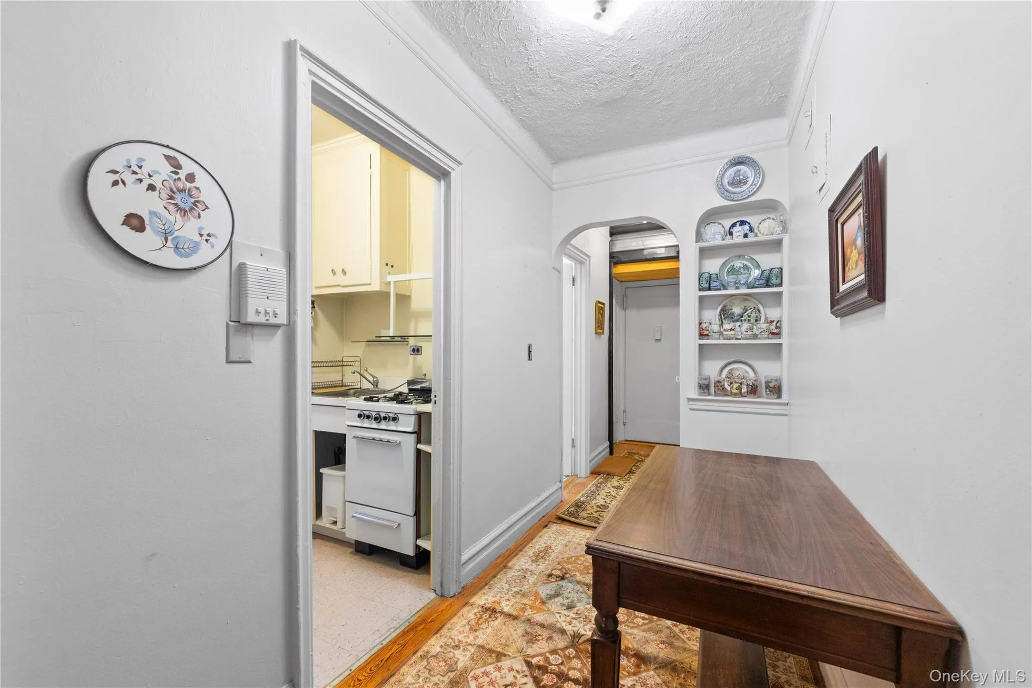 Hall with a textured ceiling, arched walkways, ornamental molding, and built in shelves Hall with a textured ceiling, arched walkways, ornamental molding, and built in shelves