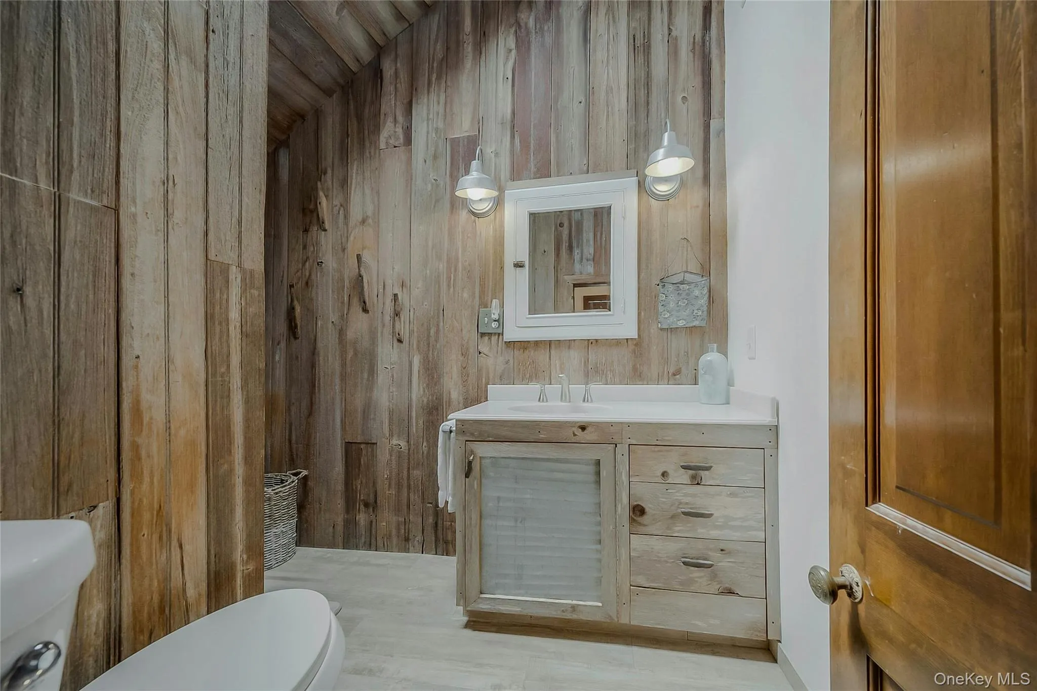 Full bath featuring toilet, wood walls, and vanity Full bath featuring toilet, wood walls, and vanity