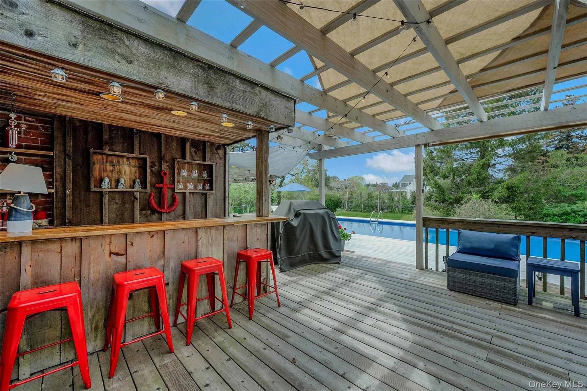 Wooden terrace featuring grilling area and an outdoor pool Wooden terrace featuring grilling area and an outdoor pool