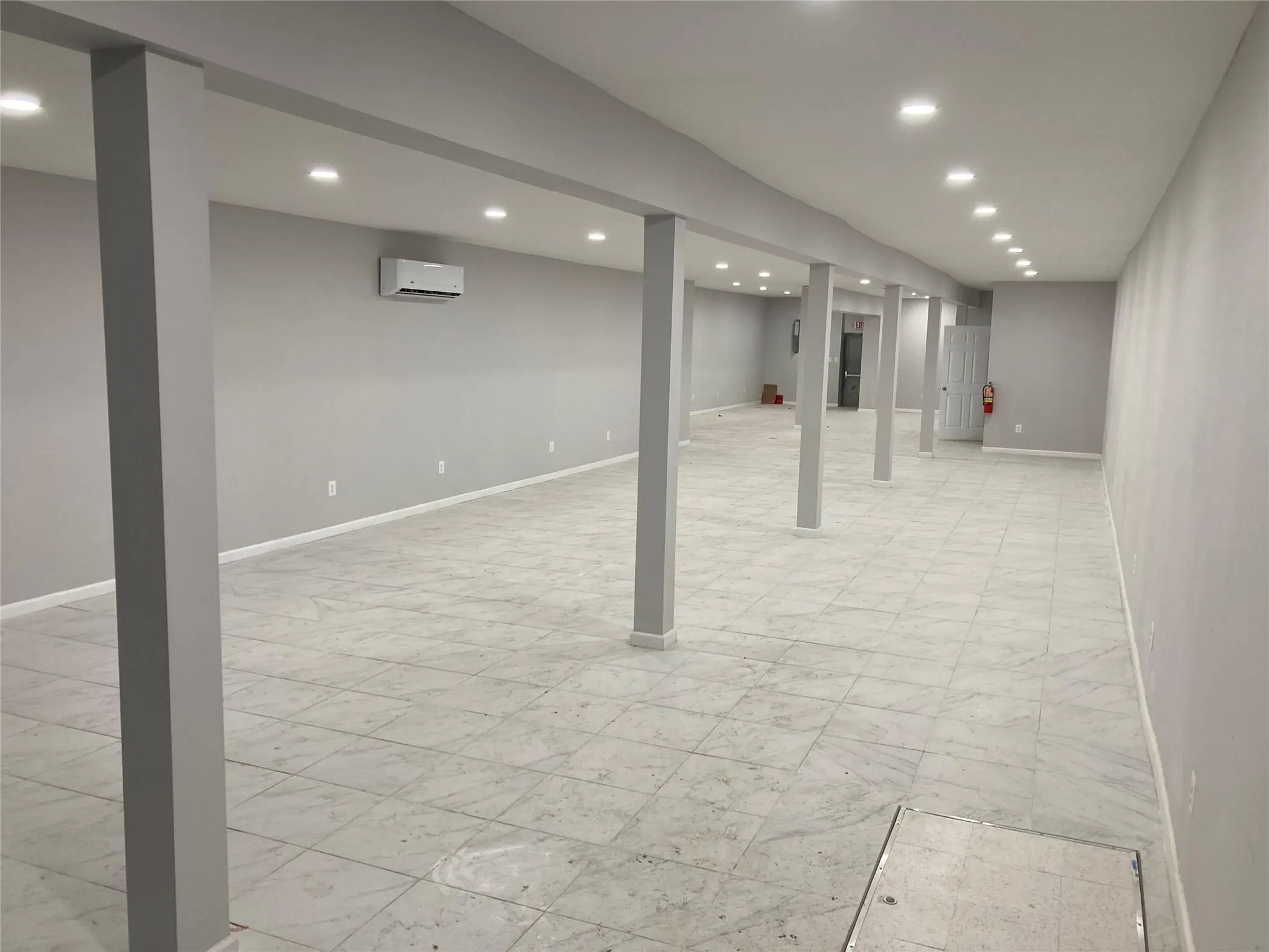 Finished basement with light marble finish floors, a wall unit AC, recessed lighting, and baseboards Finished basement with light marble finish floors, a wall unit AC, recessed lighting, and baseboards