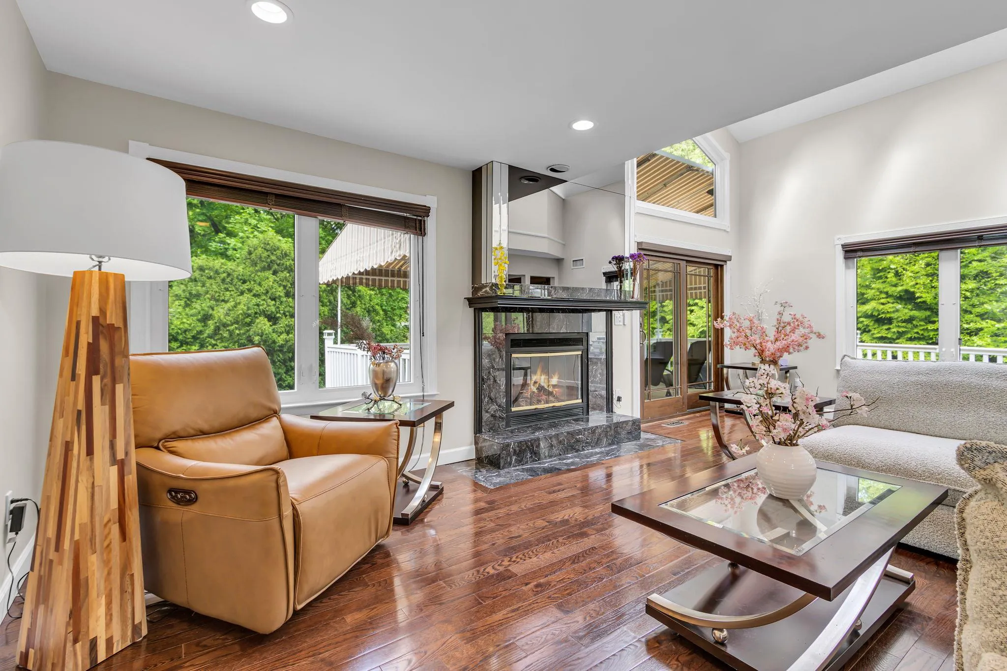 Living area featuring a tiled fireplace, hardwood / wood-style floors, recessed lighting, baseboards, and a towering ceiling Living area featuring a tiled fireplace, hardwood / wood-style floors, recessed lighting, baseboards, and a towering ceiling