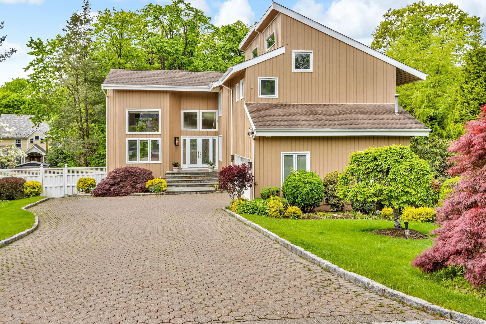 Mid-century modern home featuring french doors, roof with shingles, and decorative driveway Mid-century modern home featuring french doors, roof with shingles, and decorative driveway