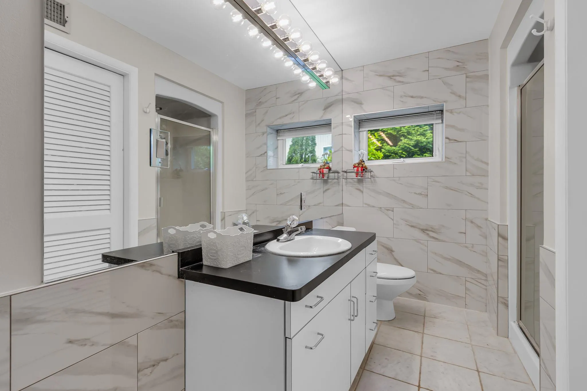 Full bathroom with vanity, tile walls, toilet, and a stall shower Full bathroom with vanity, tile walls, toilet, and a stall shower