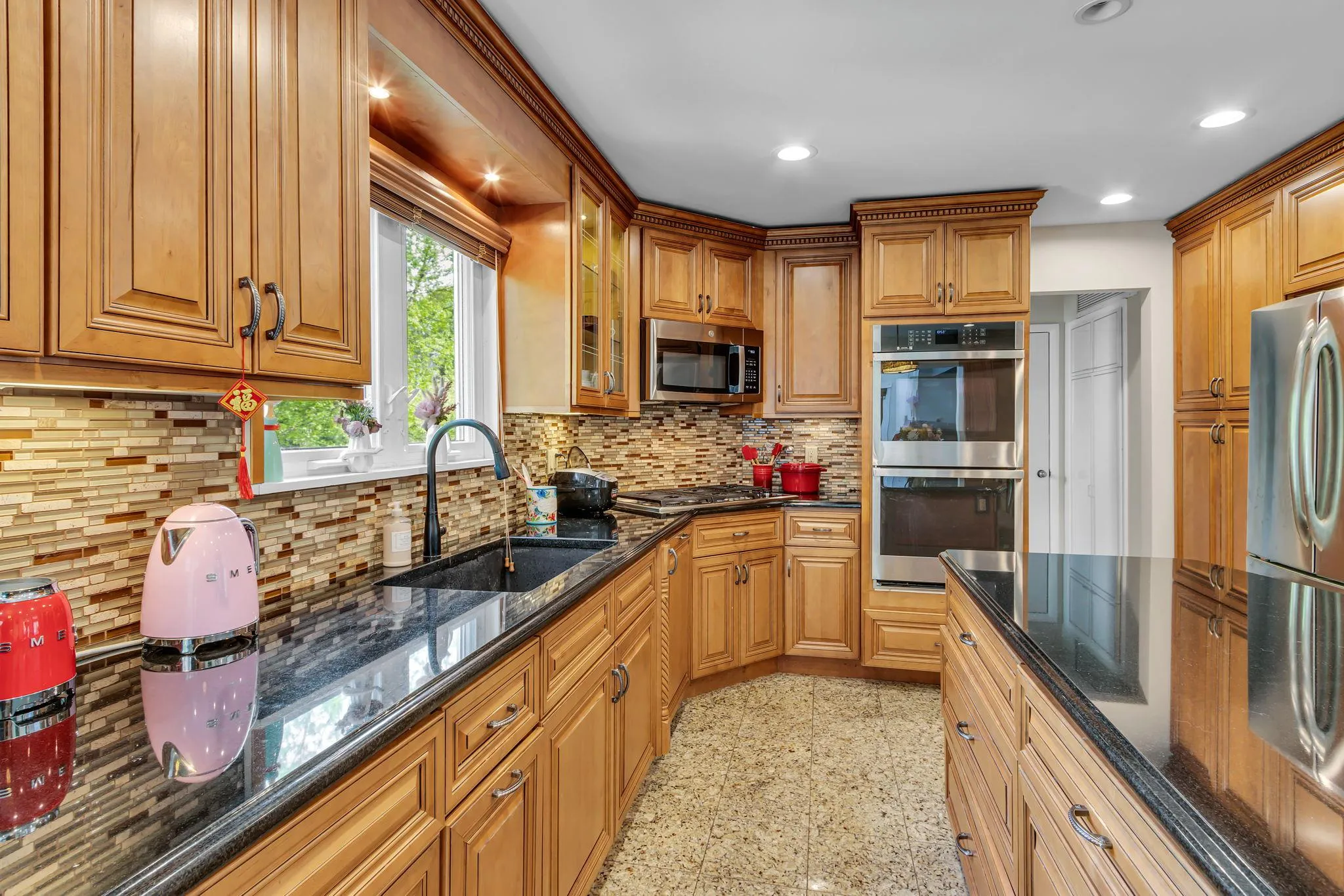 Kitchen featuring appliances with stainless steel finishes, a sink, dark stone counters, tasteful backsplash, and recessed lighting Kitchen featuring appliances with stainless steel finishes, a sink, dark stone counters, tasteful backsplash, and recessed lighting