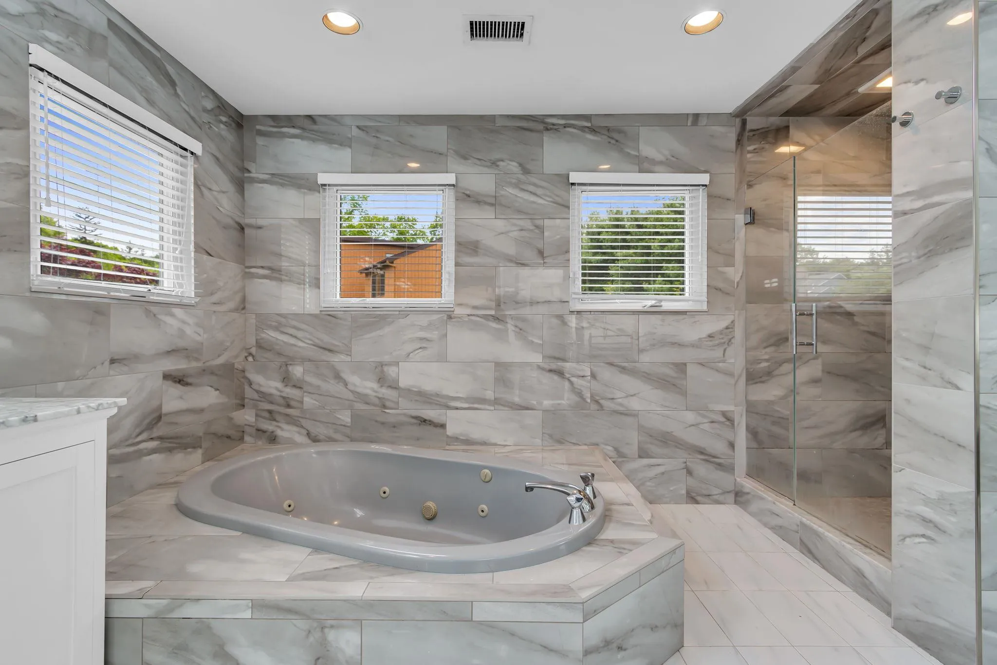 Bathroom with a whirlpool tub, a stall shower, vanity, recessed lighting, and tile walls Bathroom with a whirlpool tub, a stall shower, vanity, recessed lighting, and tile walls