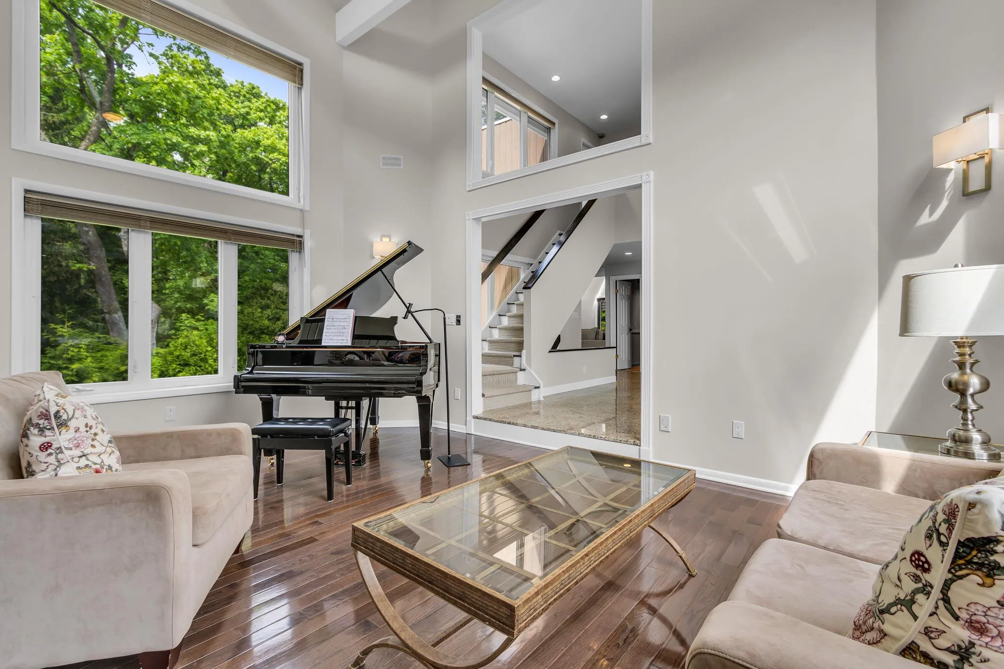 Living room featuring plenty of natural light, a towering ceiling, hardwood / wood-style floors, and recessed lighting Living room featuring plenty of natural light, a towering ceiling, hardwood / wood-style floors, and recessed lighting