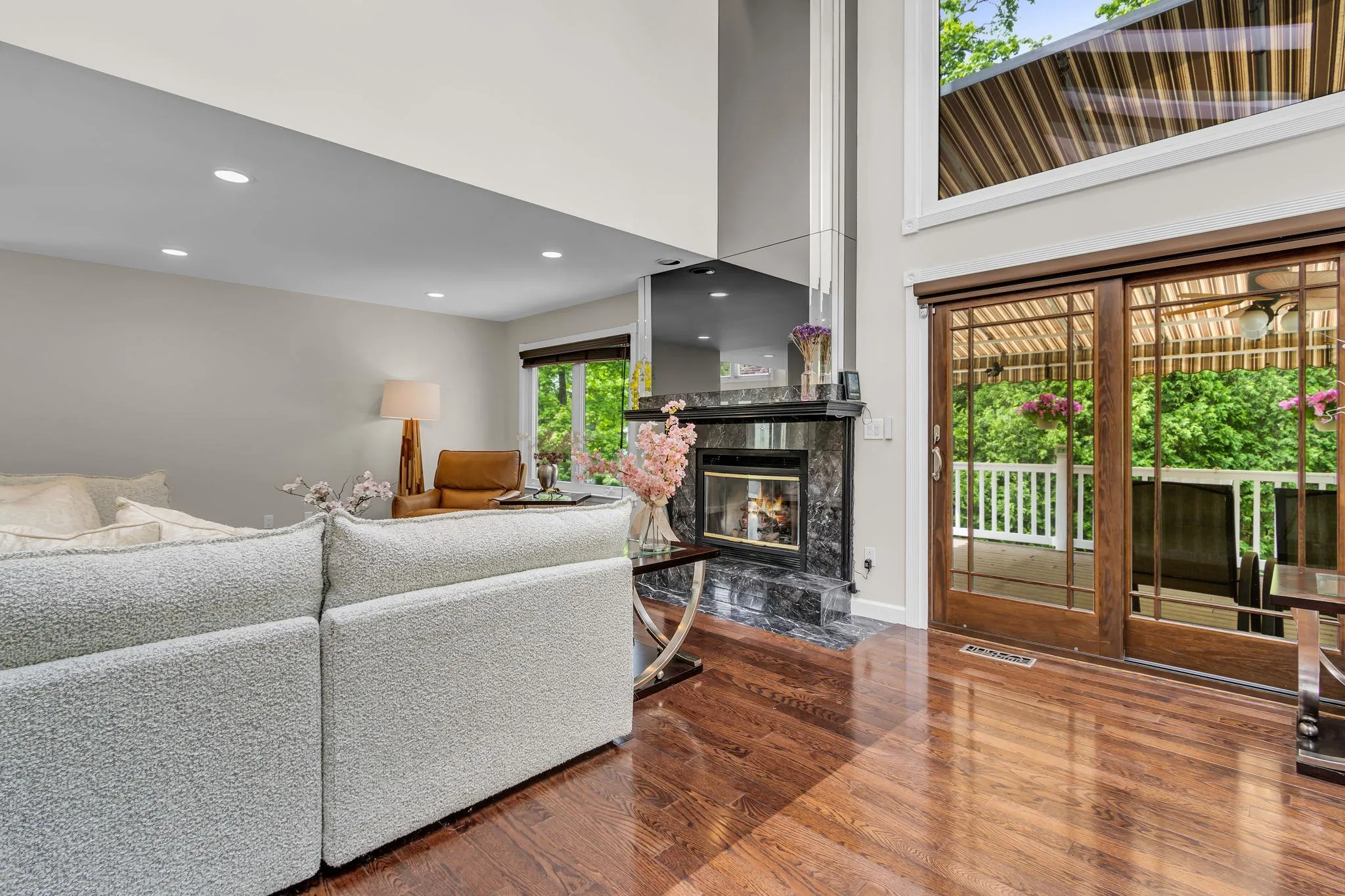 Living room featuring wood finished floors, a fireplace, recessed lighting, a towering ceiling, and baseboards Living room featuring wood finished floors, a fireplace, recessed lighting, a towering ceiling, and baseboards