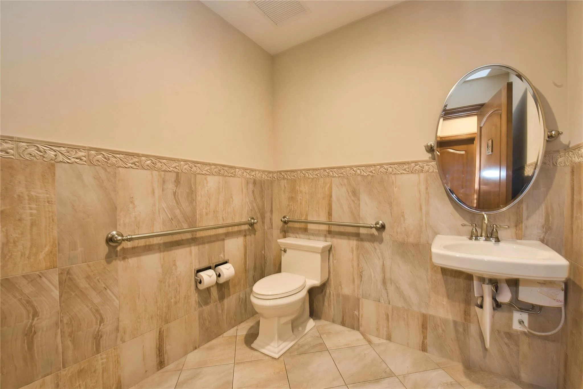 Half bath featuring tile walls, toilet, tile patterned floors, and a wainscoted wall Half bath featuring tile walls, toilet, tile patterned floors, and a wainscoted wall
