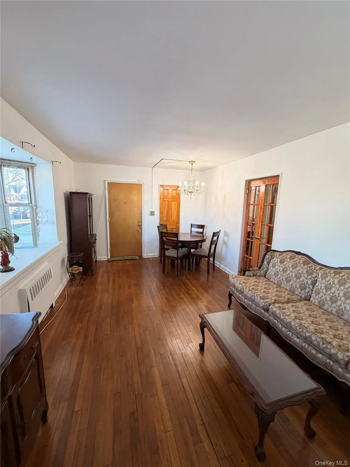 Living room with a chandelier, dark wood-style flooring, and radiator heating unit Living room with a chandelier, dark wood-style flooring, and radiator heating unit
