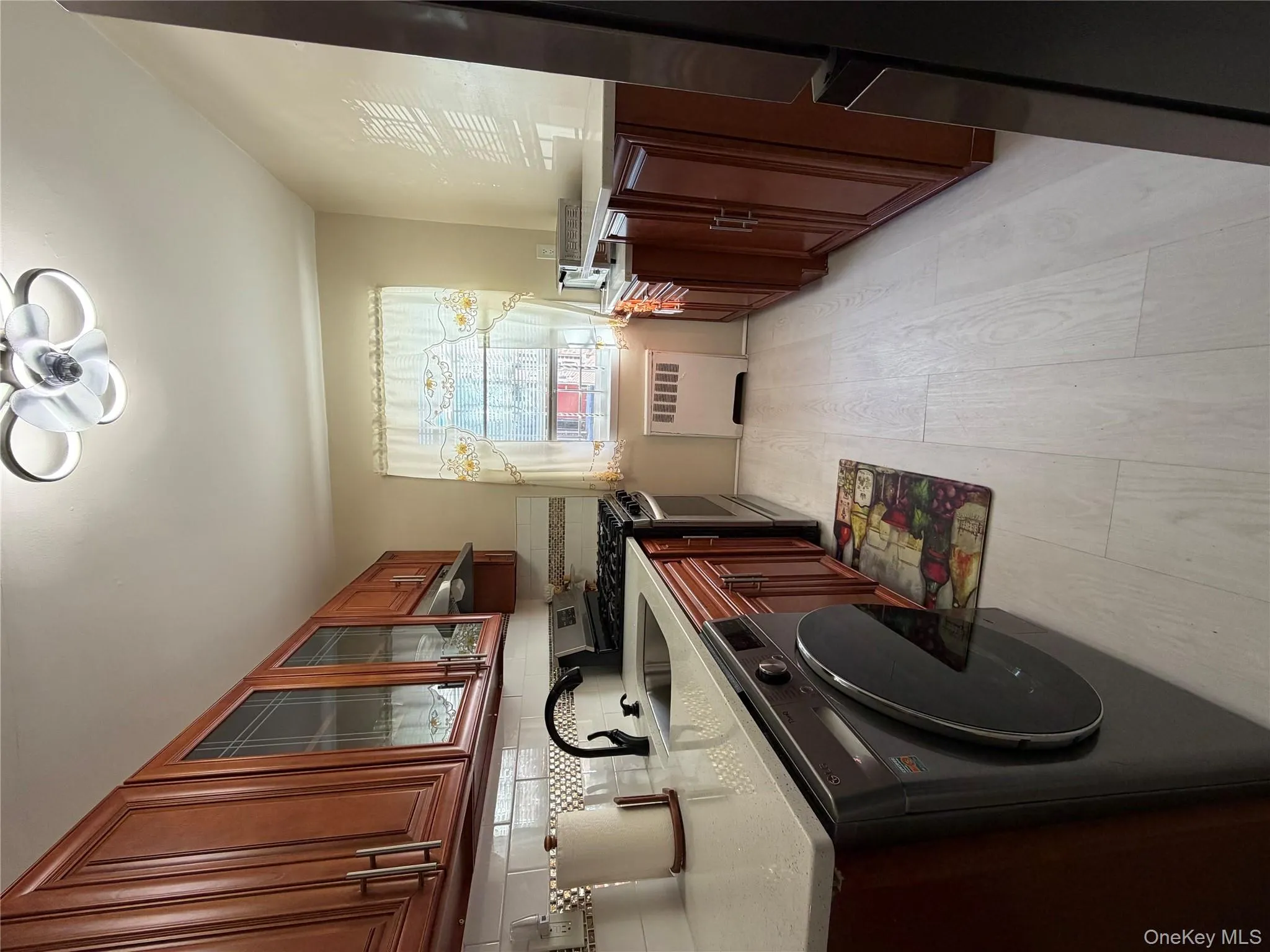 Kitchen featuring stainless steel stove, washer / dryer, glass insert cabinets, radiator heating unit, and light stone counters Kitchen featuring stainless steel stove, washer / dryer, glass insert cabinets, radiator heating unit, and light stone counters