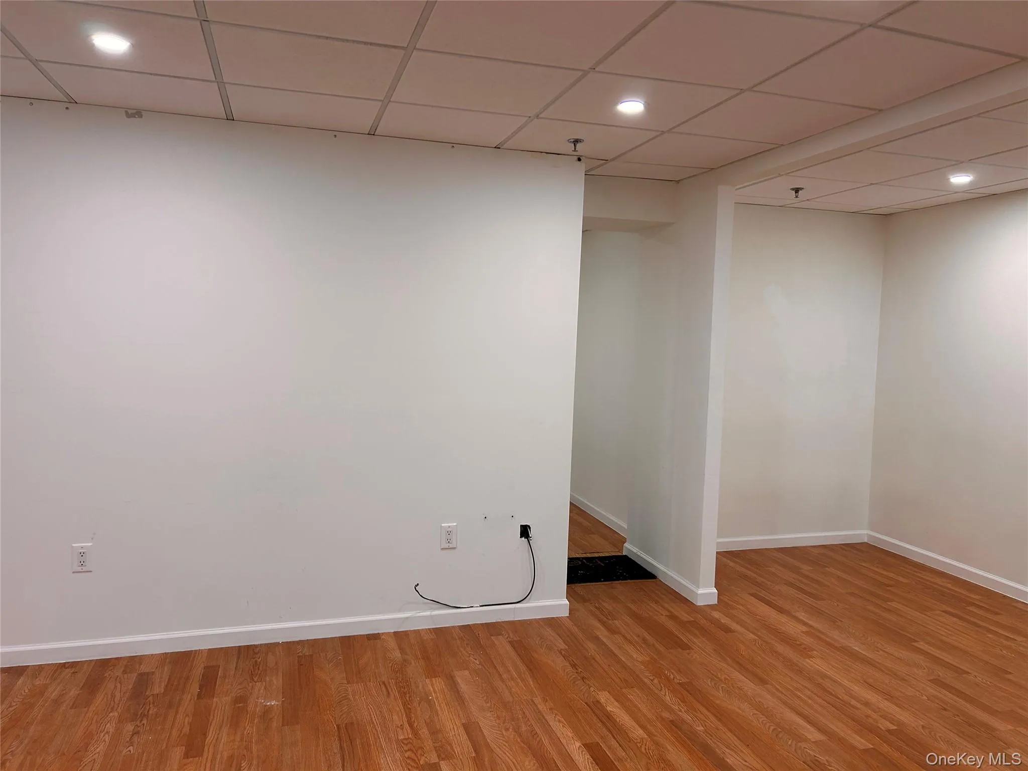 Finished basement featuring light wood-type flooring, baseboards, recessed lighting, and a paneled ceiling Finished basement featuring light wood-type flooring, baseboards, recessed lighting, and a paneled ceiling