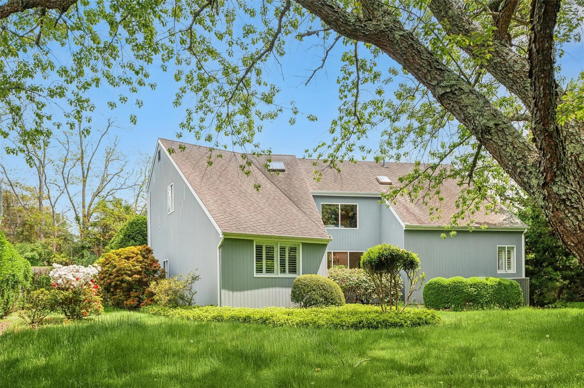 Rear view of house featuring a shingled roof and a lawn Rear view of house featuring a shingled roof and a lawn