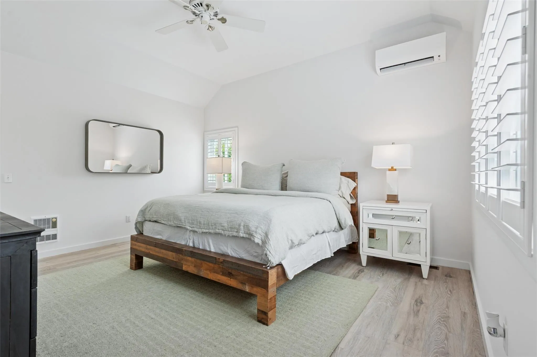 Bedroom featuring a wall mounted air conditioner, light wood-style floors, lofted ceiling, baseboards, and ceiling fan Bedroom featuring a wall mounted air conditioner, light wood-style floors, lofted ceiling, baseboards, and ceiling fan