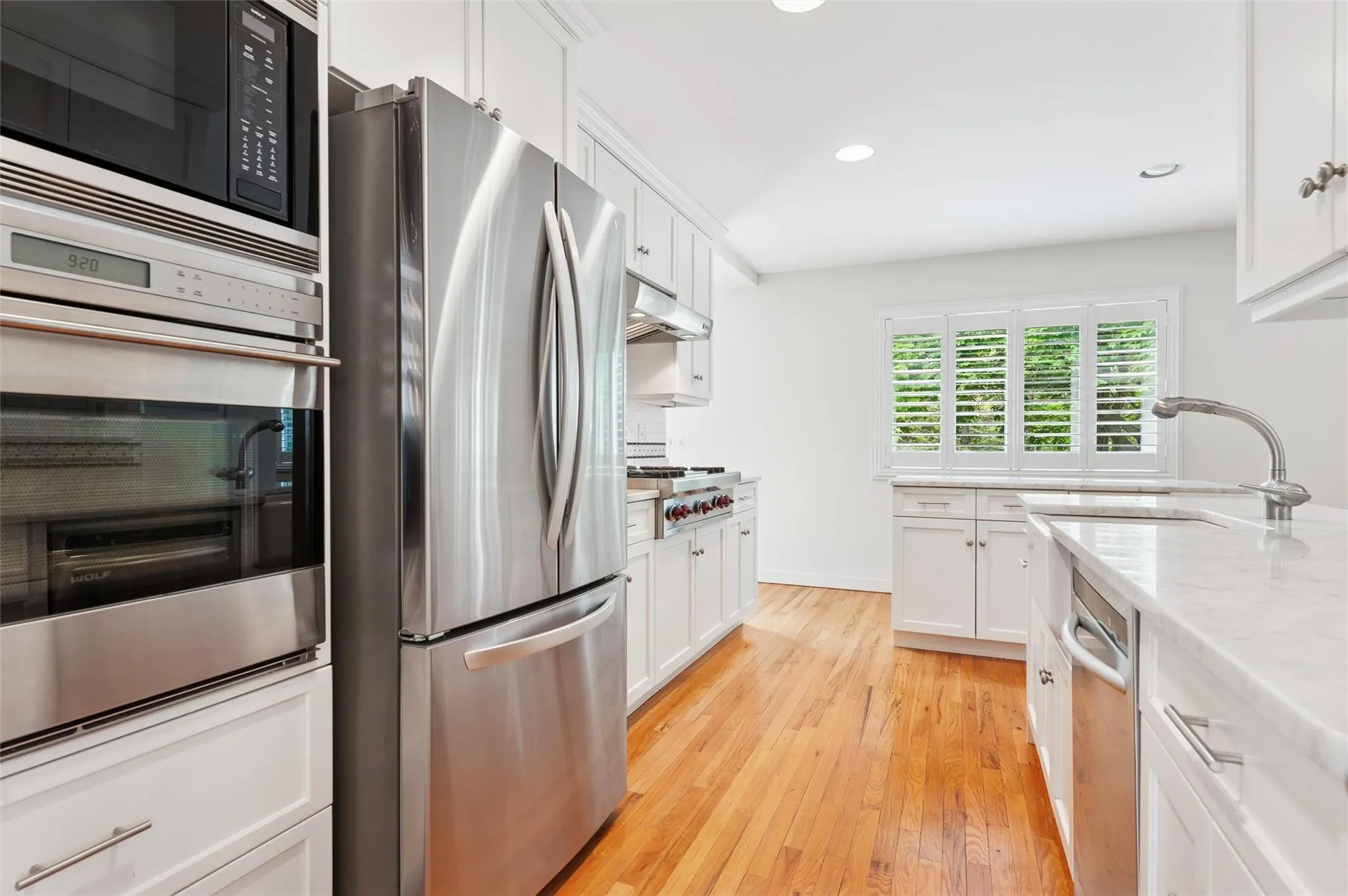 Kitchen featuring stainless steel appliances, a sink, recessed lighting, white cabinetry, and light wood finished floors Kitchen featuring stainless steel appliances, a sink, recessed lighting, white cabinetry, and light wood finished floors