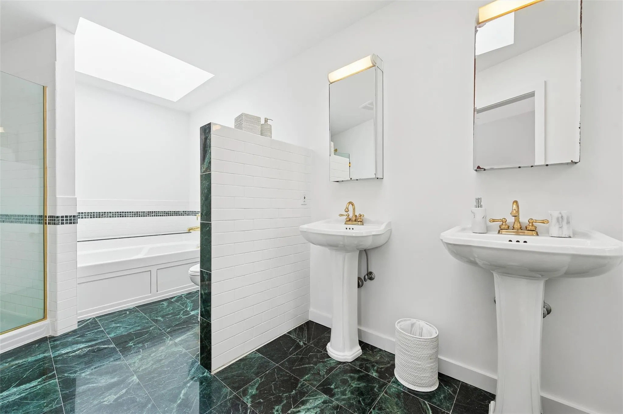 Full bath featuring a skylight, marble finish floors, a garden tub, a shower, and baseboards Full bath featuring a skylight, marble finish floors, a garden tub, a shower, and baseboards