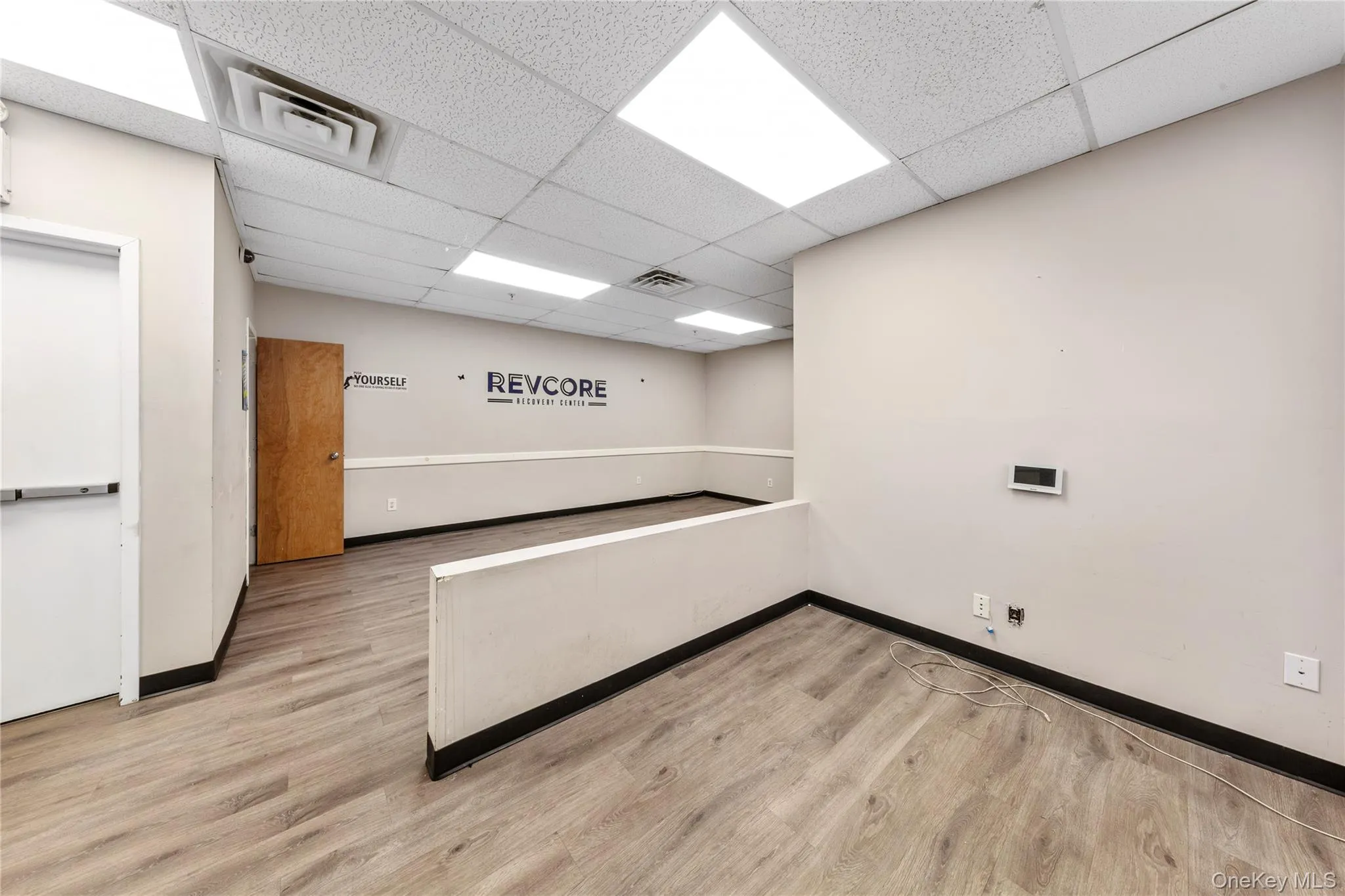 Empty room featuring baseboards, a paneled ceiling, and wood finished floors Empty room featuring baseboards, a paneled ceiling, and wood finished floors