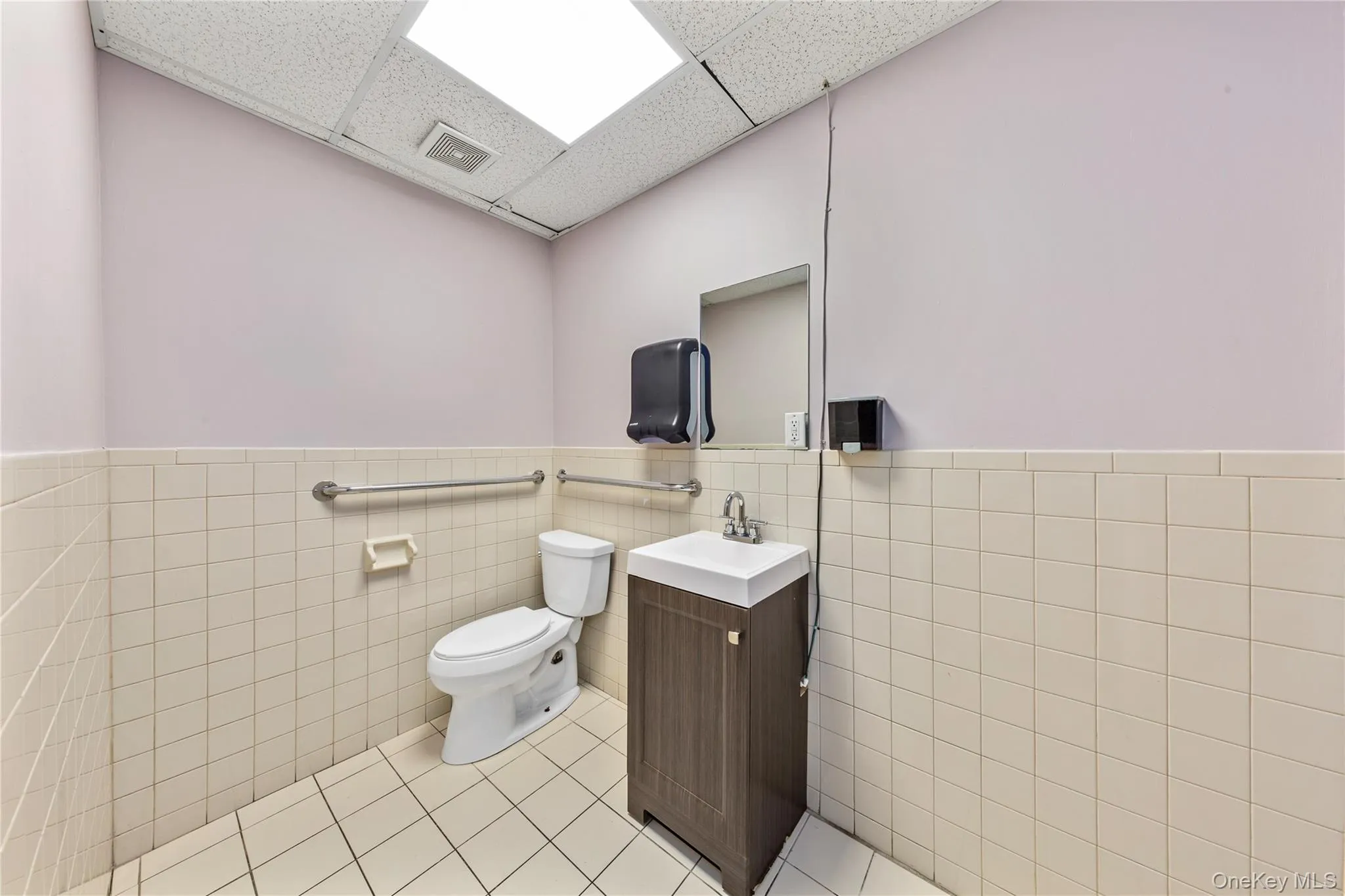 Bathroom featuring vanity, tile walls, a paneled ceiling, toilet, and tile patterned floors Bathroom featuring vanity, tile walls, a paneled ceiling, toilet, and tile patterned floors