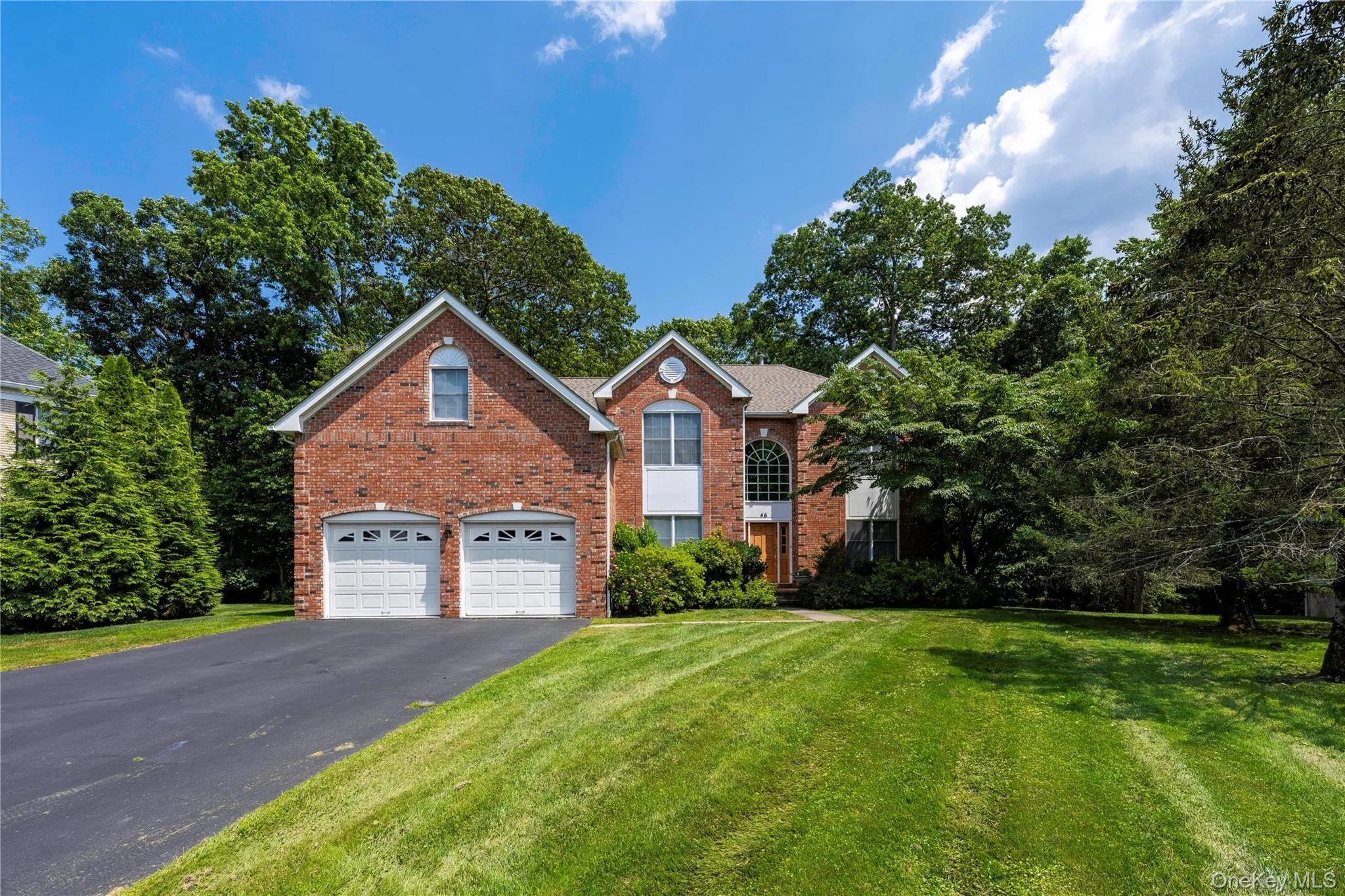 Traditional home featuring driveway, brick siding, a front lawn, and a garage Traditional home featuring driveway, brick siding, a front lawn, and a garage