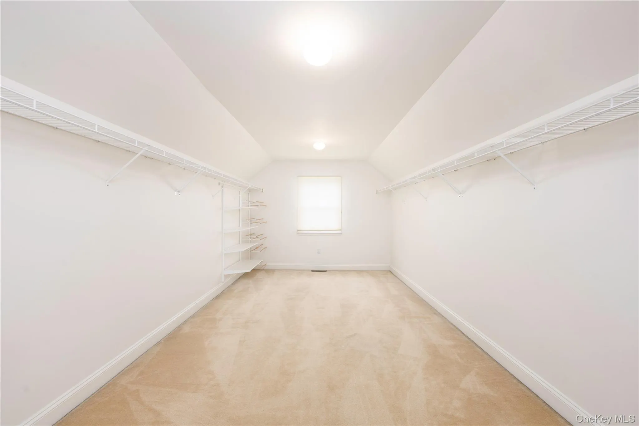 Spacious closet with vaulted ceiling and light colored carpet Spacious closet with vaulted ceiling and light colored carpet