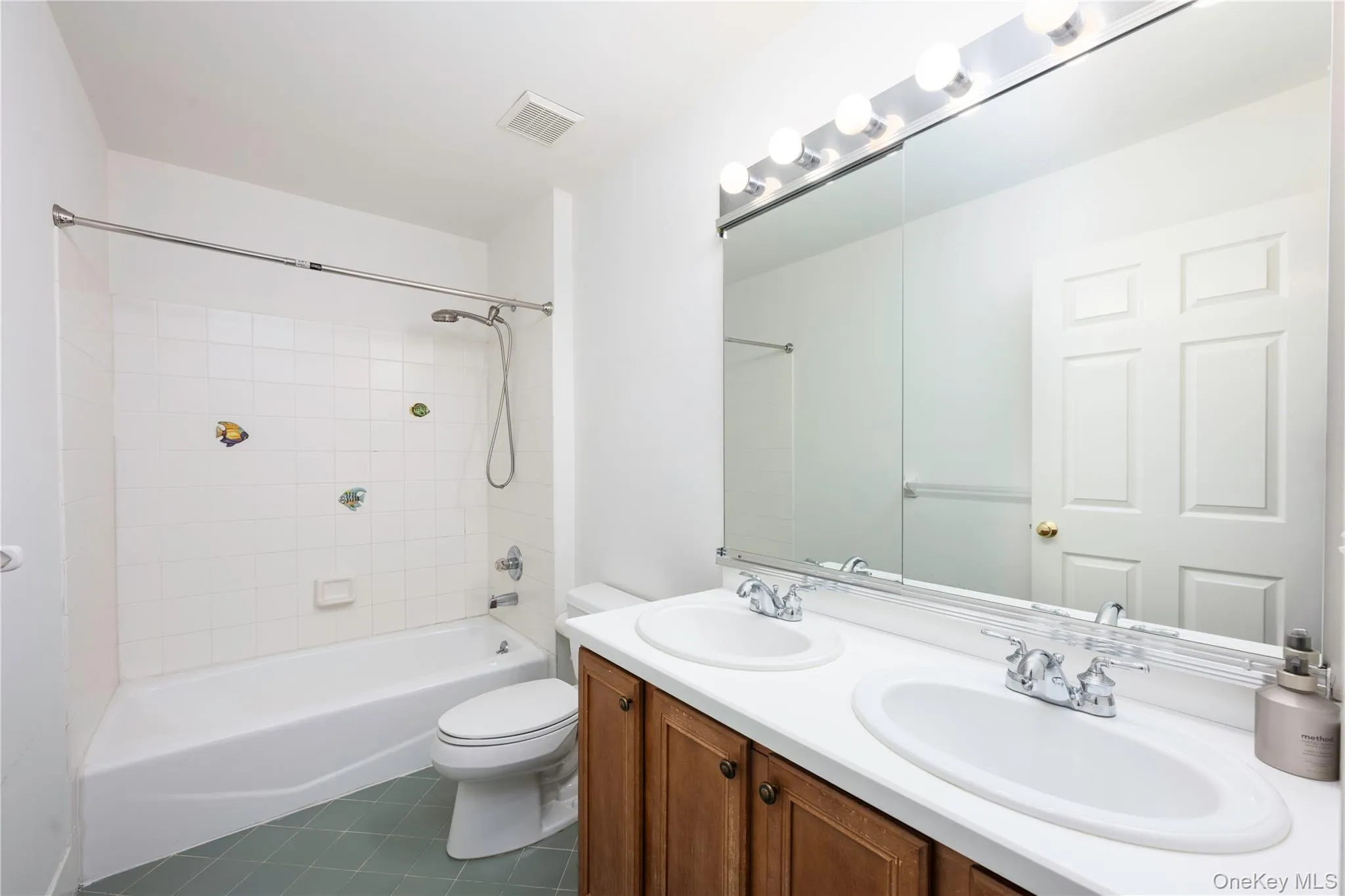 Full bathroom with tile patterned flooring, double vanity, and shower / washtub combination Full bathroom with tile patterned flooring, double vanity, and shower / washtub combination