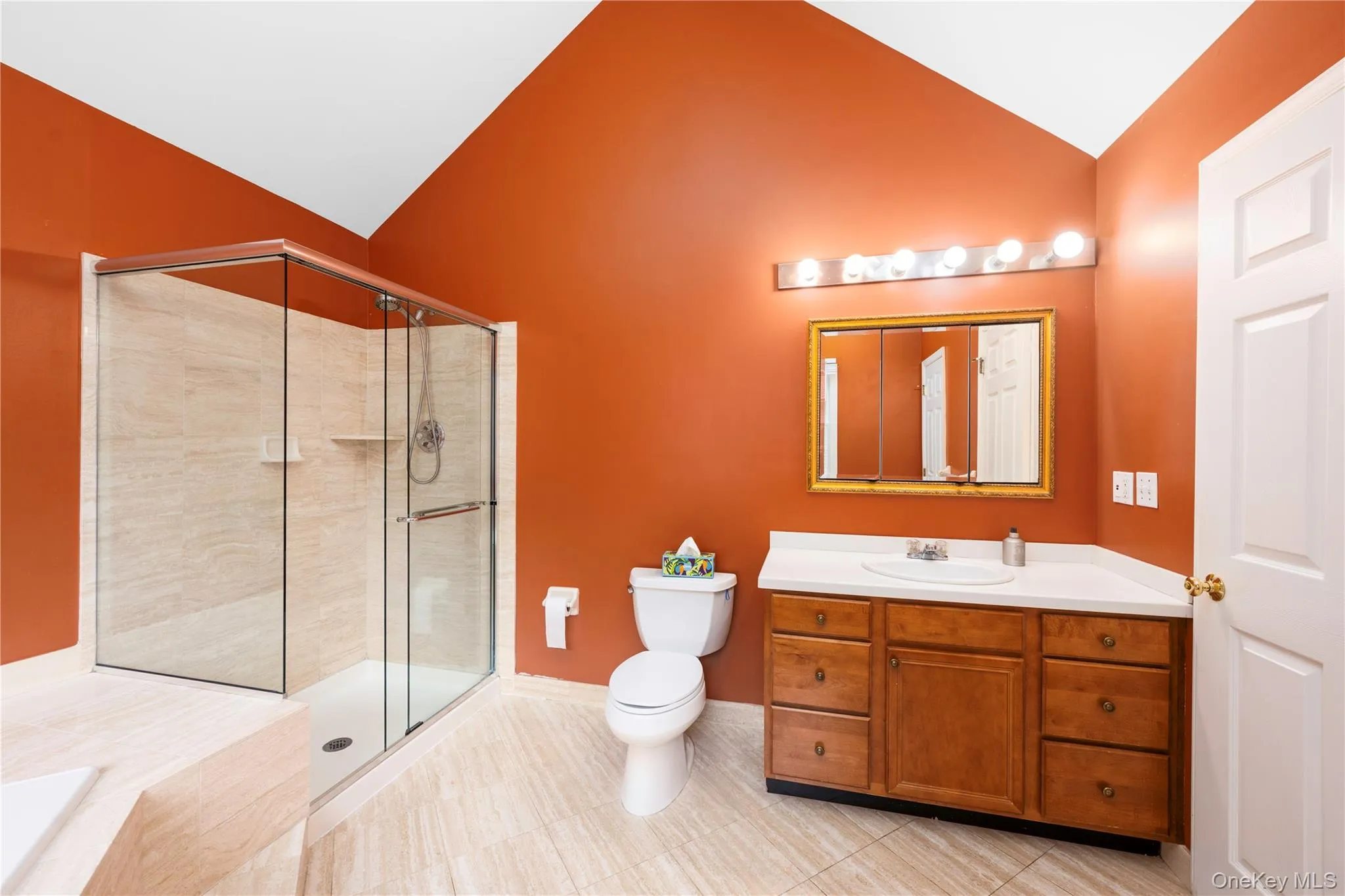 Full bath featuring vaulted ceiling, vanity, a stall shower, a bath, and tile patterned floors Full bath featuring vaulted ceiling, vanity, a stall shower, a bath, and tile patterned floors