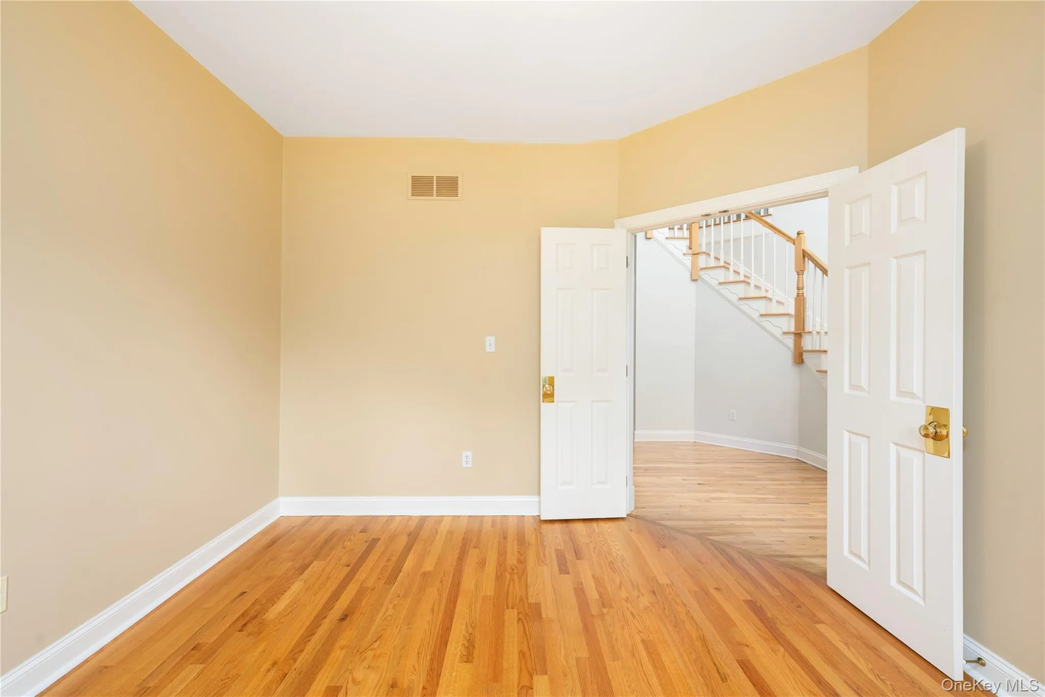 Spare room featuring light wood-style flooring and stairs Spare room featuring light wood-style flooring and stairs