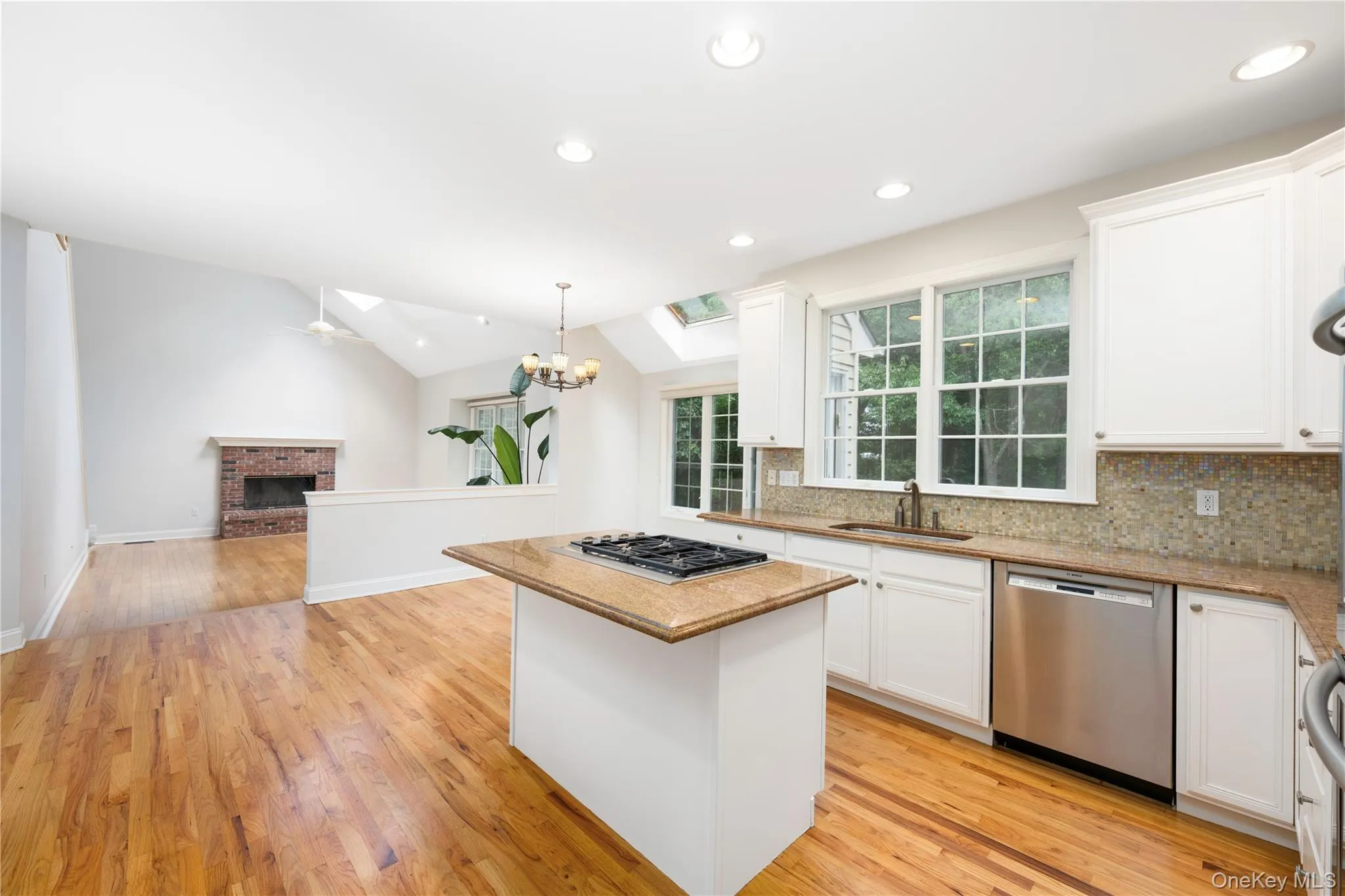 Kitchen with stainless steel appliances, a chandelier, a kitchen island, tasteful backsplash, and white cabinetry Kitchen with stainless steel appliances, a chandelier, a kitchen island, tasteful backsplash, and white cabinetry