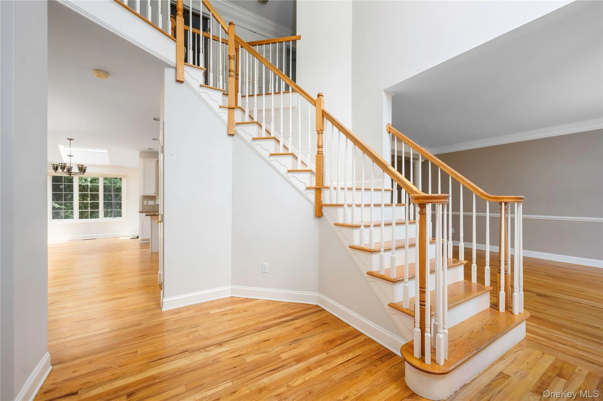 Staircase featuring wood finished floors, a high ceiling, ornamental molding, and a chandelier Staircase featuring wood finished floors, a high ceiling, ornamental molding, and a chandelier