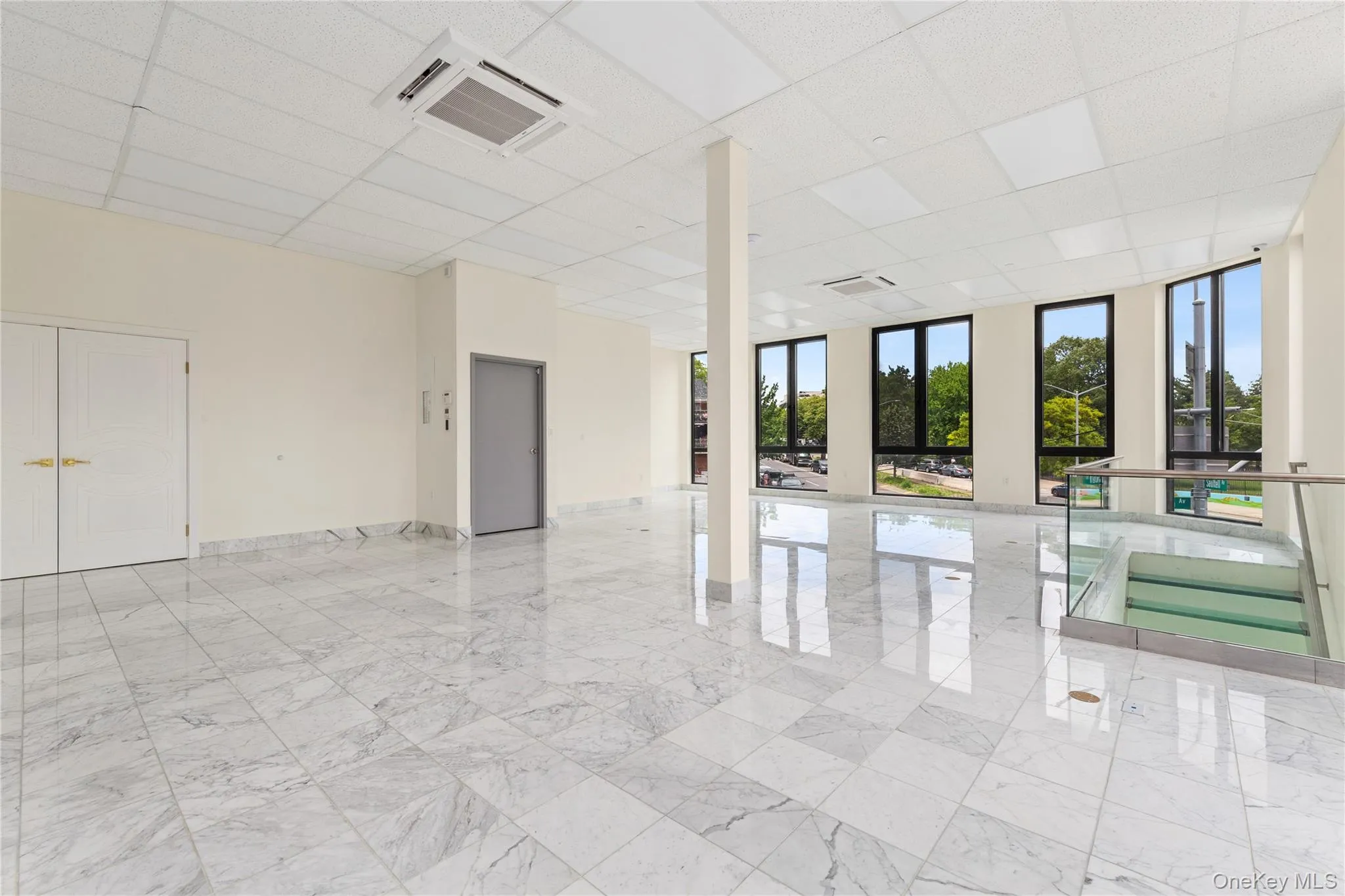 Unfurnished room featuring a paneled ceiling, light marble finish flooring, and baseboards Unfurnished room featuring a paneled ceiling, light marble finish flooring, and baseboards