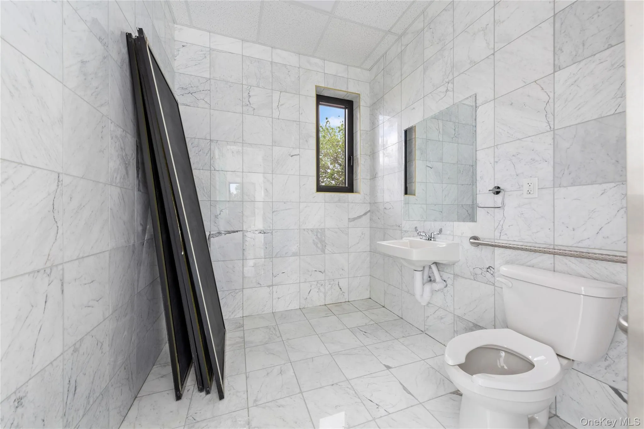 Bathroom featuring toilet, tile walls, and a sink Bathroom featuring toilet, tile walls, and a sink