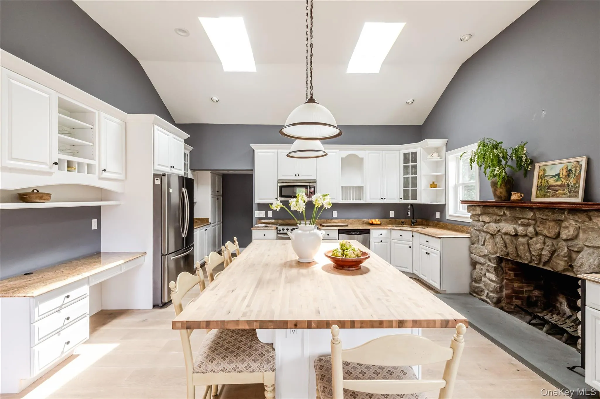 Kitchen featuring open shelves, appliances with stainless steel finishes, a skylight, white cabinets, and a breakfast bar area Kitchen featuring open shelves, appliances with stainless steel finishes, a skylight, white cabinets, and a breakfast bar area