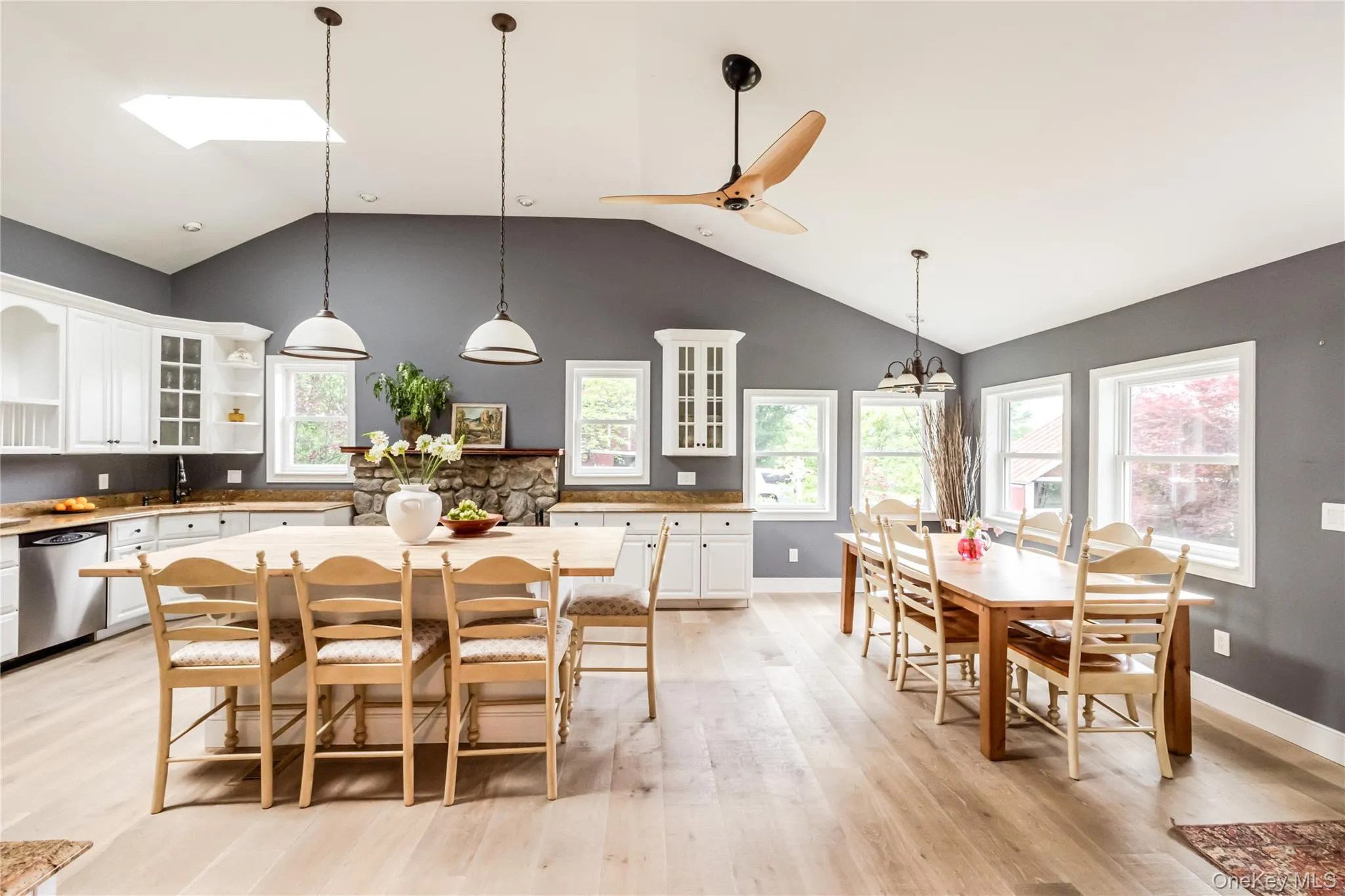 Dining room featuring high vaulted ceiling, light wood-style flooring, a chandelier, baseboards, and ceiling fan Dining room featuring high vaulted ceiling, light wood-style flooring, a chandelier, baseboards, and ceiling fan