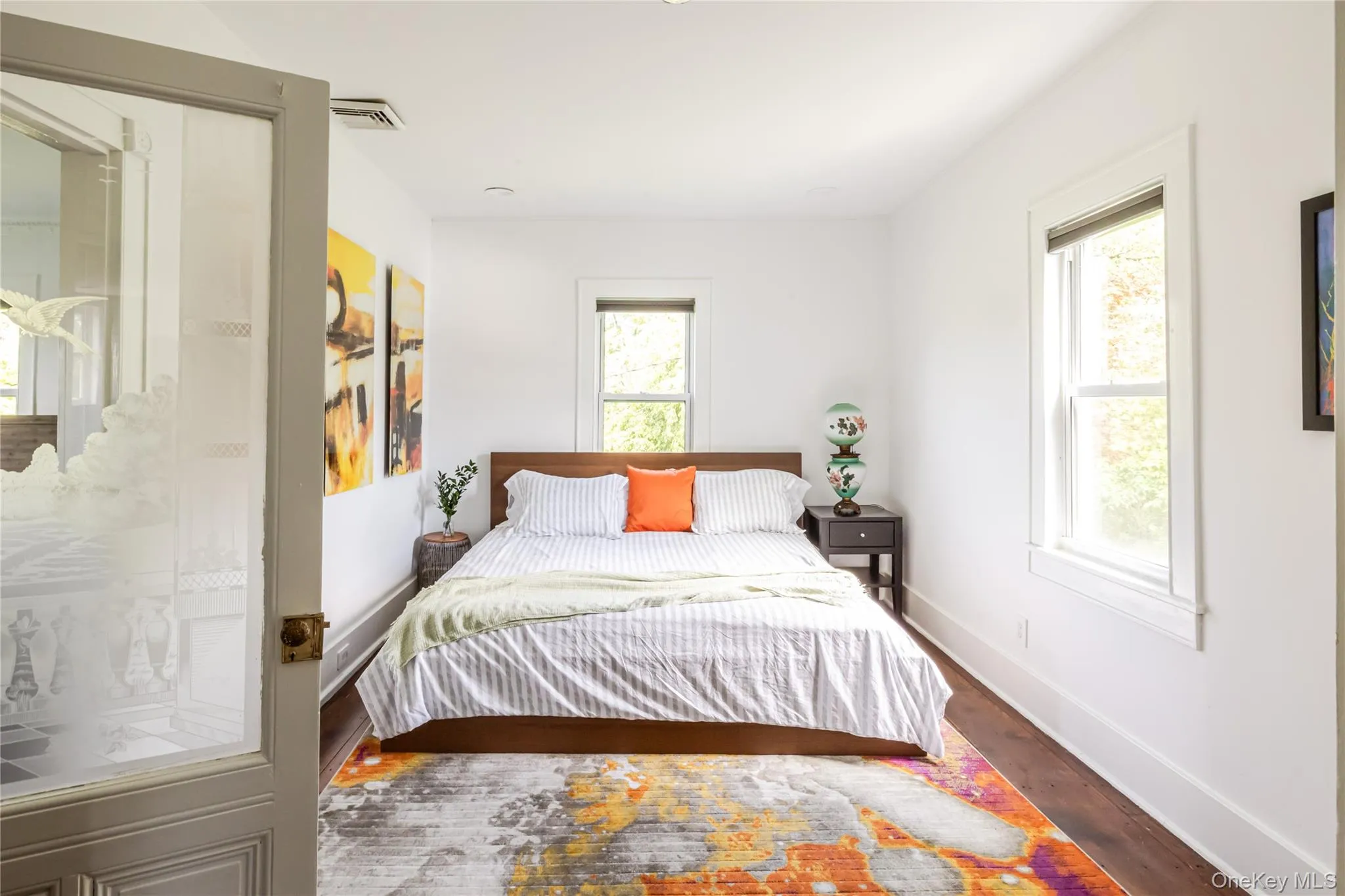 Bedroom featuring multiple windows, dark wood-style flooring, and baseboards Bedroom featuring multiple windows, dark wood-style flooring, and baseboards