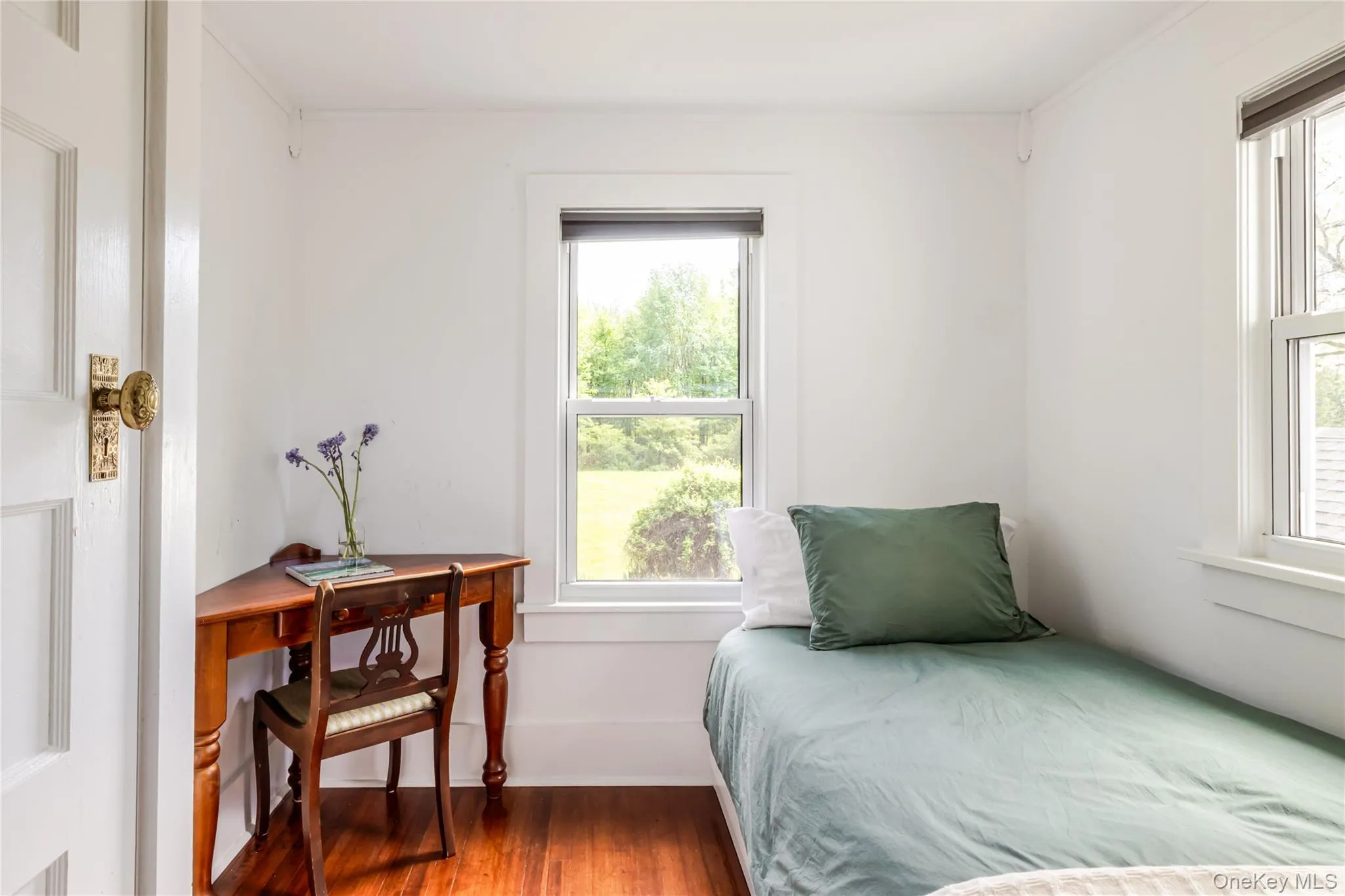 Bedroom with wood finished floors, multiple windows, and crown molding Bedroom with wood finished floors, multiple windows, and crown molding