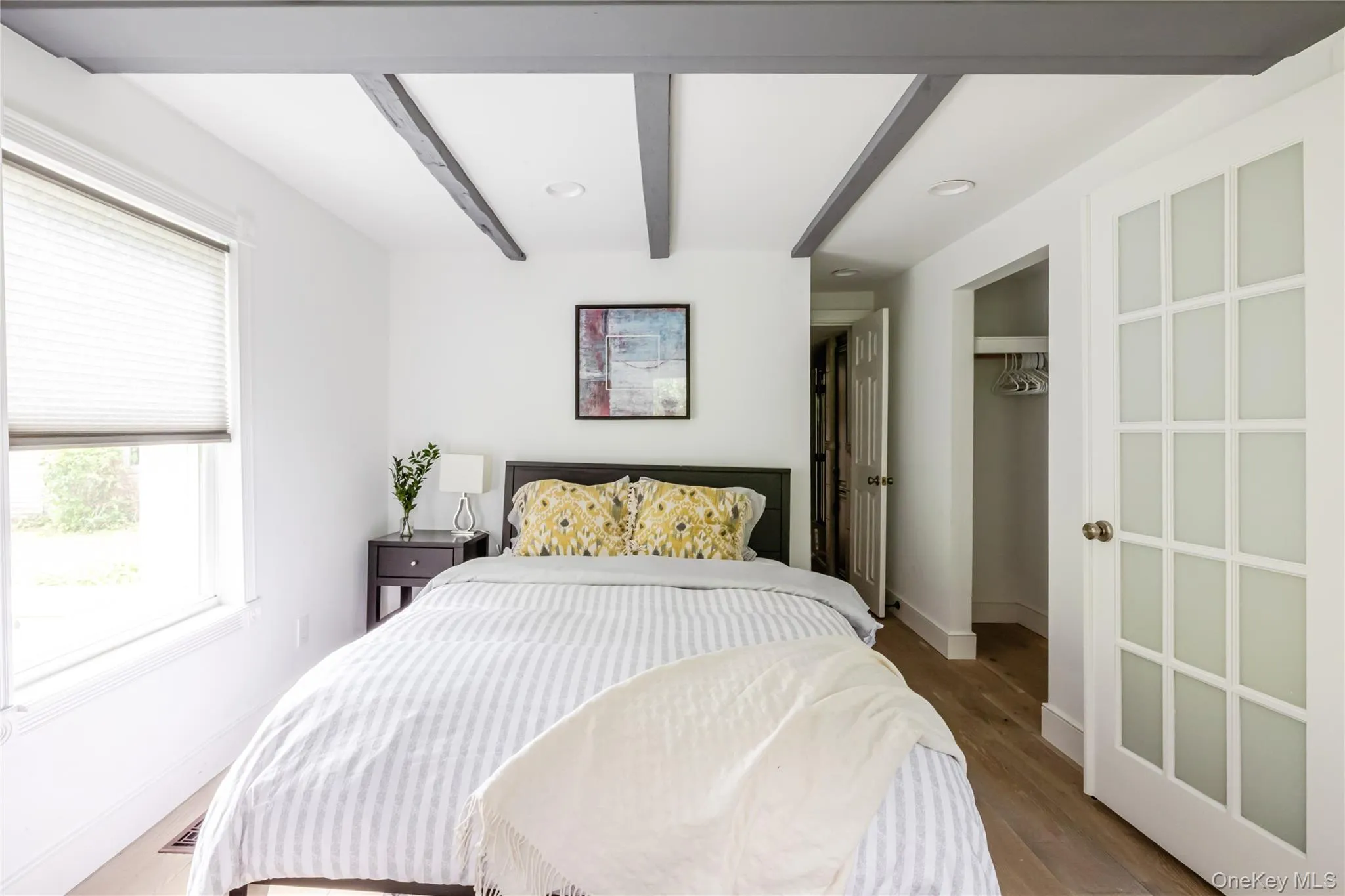 Bedroom with multiple windows, beamed ceiling, wood finished floors, baseboards, and recessed lighting Bedroom with multiple windows, beamed ceiling, wood finished floors, baseboards, and recessed lighting