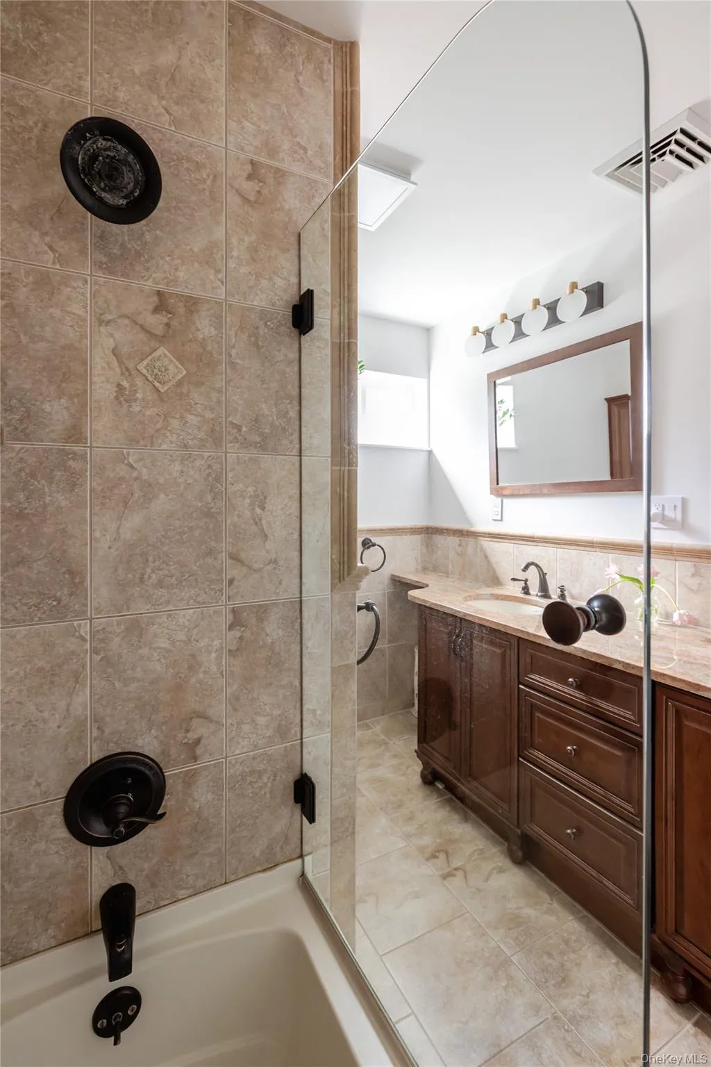 Full bath with tile walls, vanity, shower / bathtub combination, and a wainscoted wall Full bath with tile walls, vanity, shower / bathtub combination, and a wainscoted wall