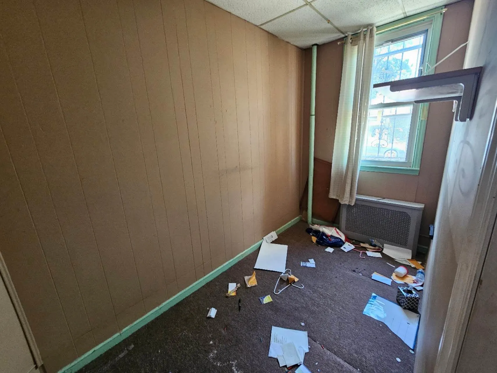 Spare room featuring wooden walls, baseboards, a drop ceiling, carpet flooring, and radiator Spare room featuring wooden walls, baseboards, a drop ceiling, carpet flooring, and radiator