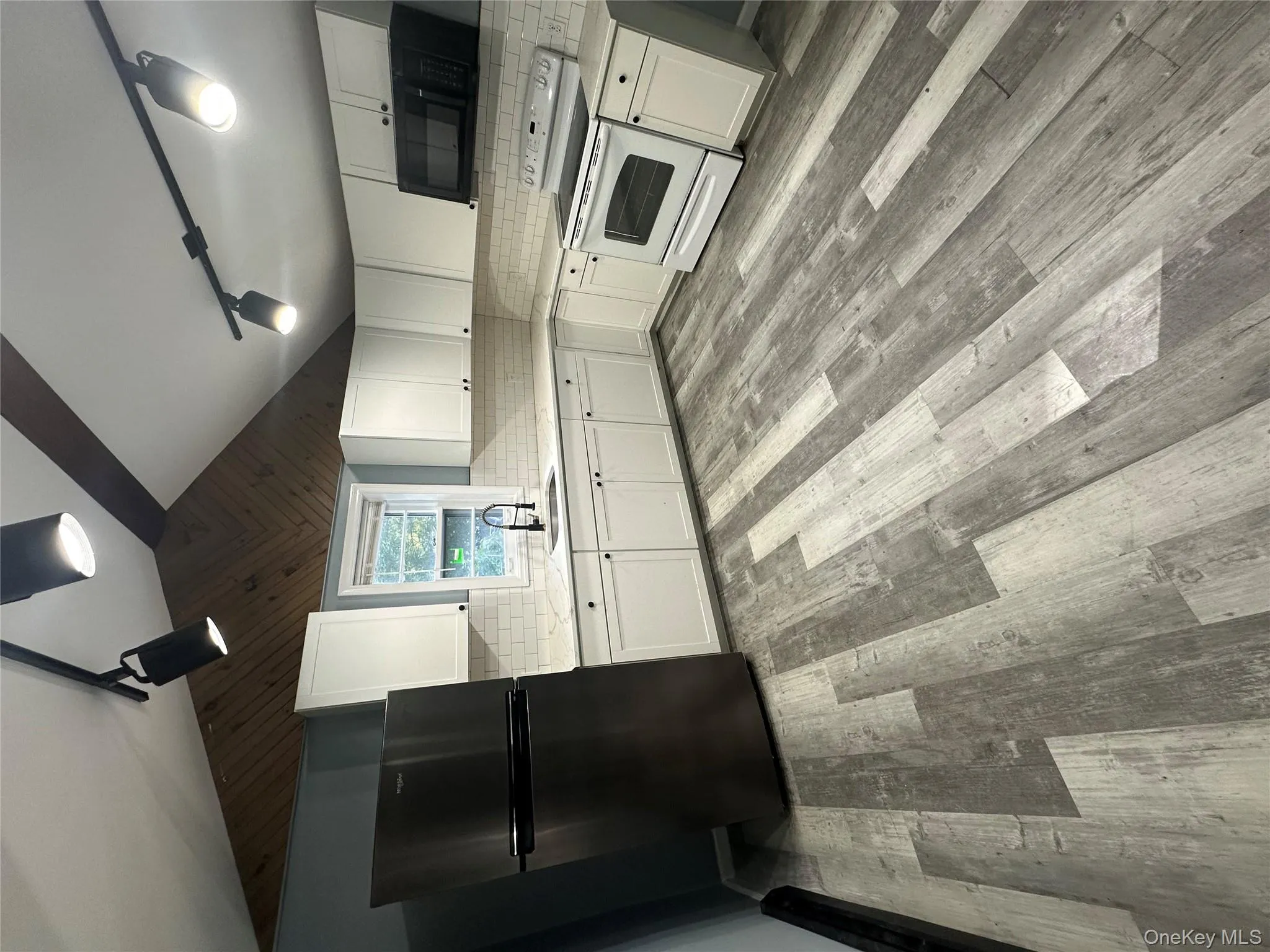 Kitchen featuring rail lighting, white cabinets, lofted ceiling, stove, and fridge Kitchen featuring rail lighting, white cabinets, lofted ceiling, stove, and fridge