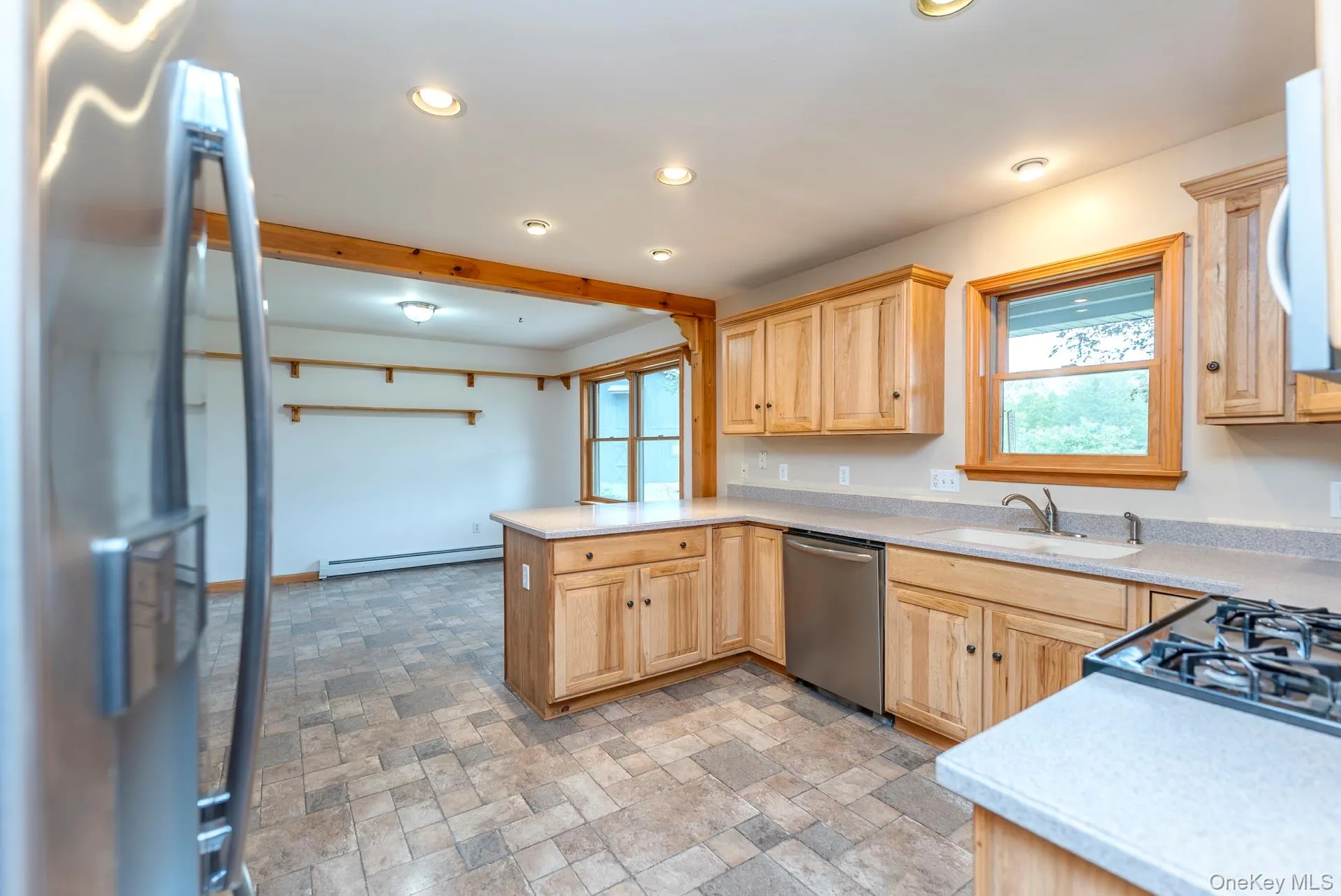 Kitchen featuring appliances with stainless steel finishes, baseboard heating, light brown cabinets, a sink, and recessed lighting Kitchen featuring appliances with stainless steel finishes, baseboard heating, light brown cabinets, a sink, and recessed lighting