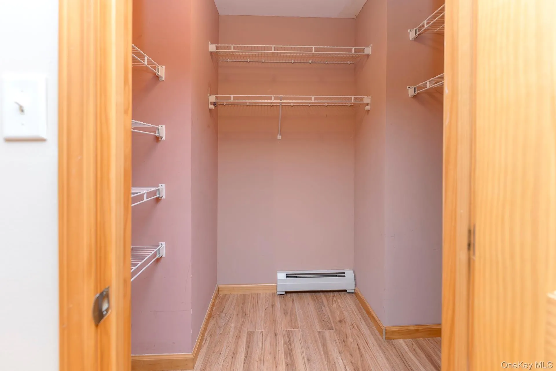 Spacious closet with a baseboard heating unit and wood finished floors Spacious closet with a baseboard heating unit and wood finished floors