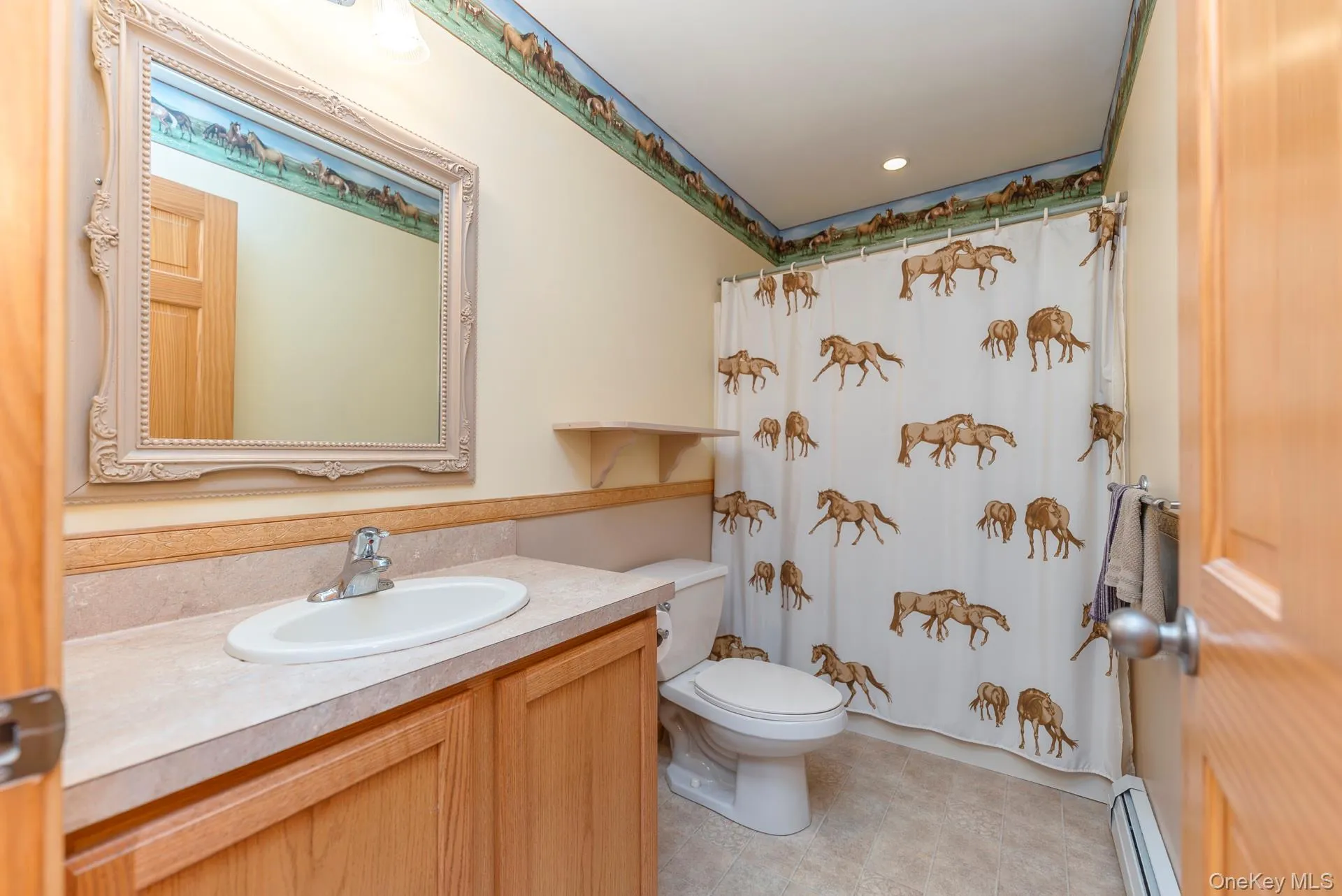 Full bath featuring a baseboard heating unit, toilet, vanity, curtained shower, and tile patterned flooring Full bath featuring a baseboard heating unit, toilet, vanity, curtained shower, and tile patterned flooring