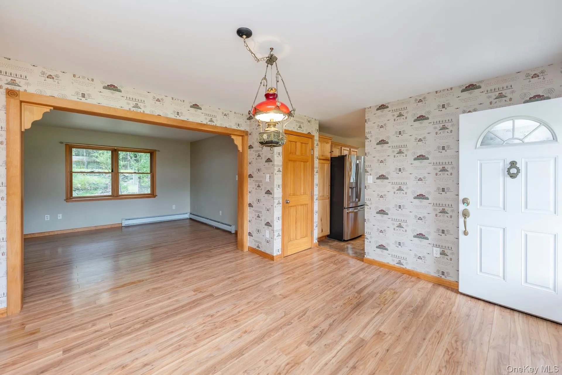 Entrance foyer featuring wallpapered walls, baseboards, light wood-style floors, a baseboard radiator, and a baseboard heating unit Entrance foyer featuring wallpapered walls, baseboards, light wood-style floors, a baseboard radiator, and a baseboard heating unit