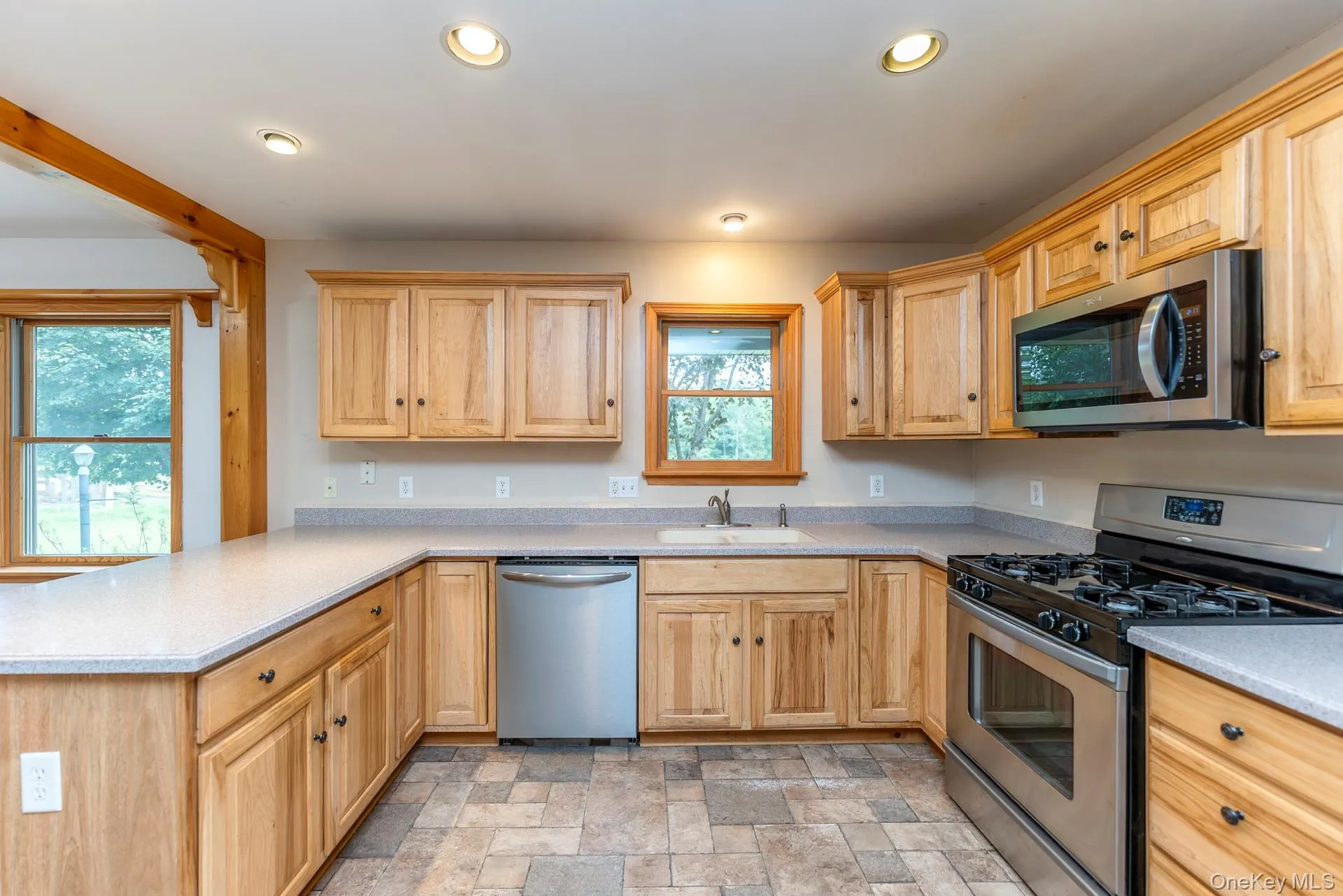 Kitchen featuring appliances with stainless steel finishes, a sink, a peninsula, recessed lighting, and stone finish flooring Kitchen featuring appliances with stainless steel finishes, a sink, a peninsula, recessed lighting, and stone finish flooring