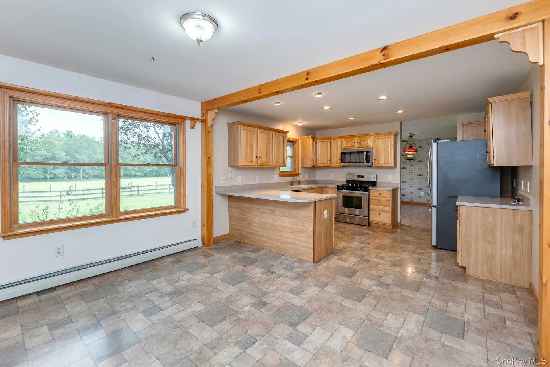 Kitchen with stainless steel appliances, baseboard heating, a peninsula, light countertops, and recessed lighting Kitchen with stainless steel appliances, baseboard heating, a peninsula, light countertops, and recessed lighting